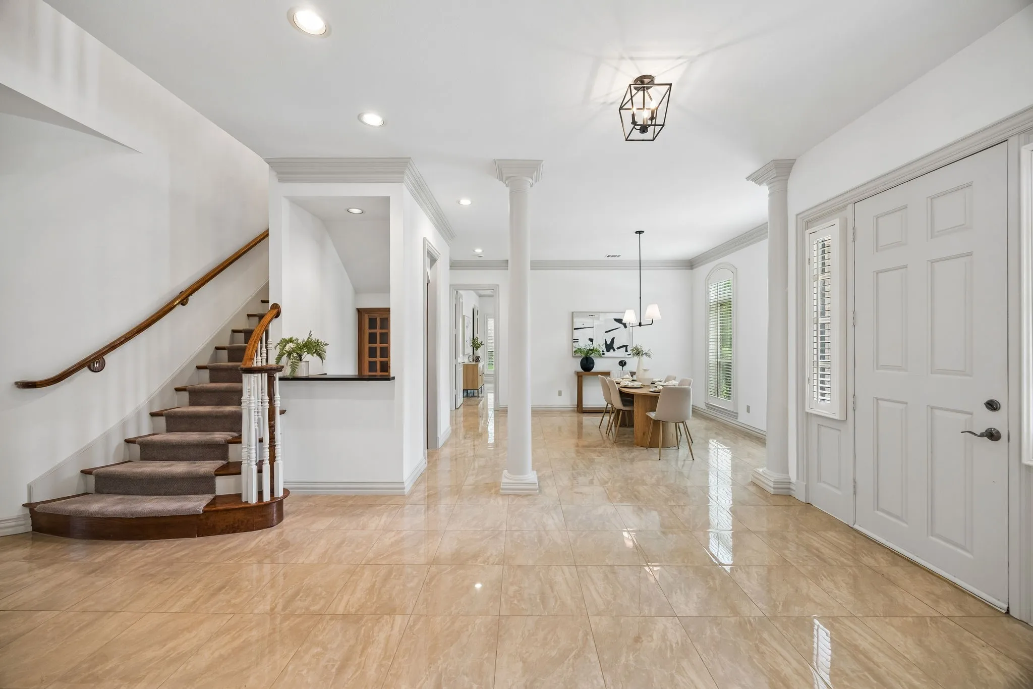 Foyer with polished tile flooring, a curved staircase with carpeted treads and wood handrail, and a formal entry door with sidelight and shutters