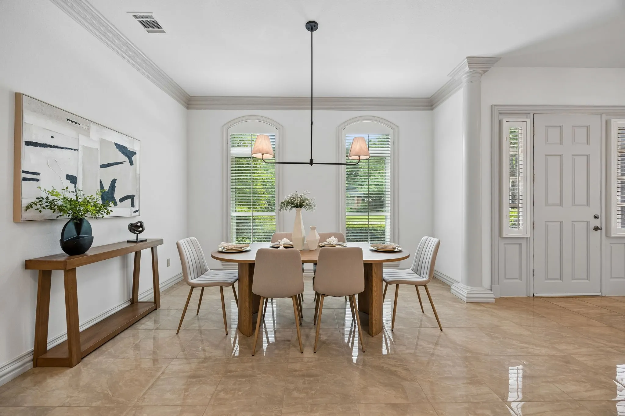 Spacious room featuring polished tile flooring, crown molding, and two arched windows