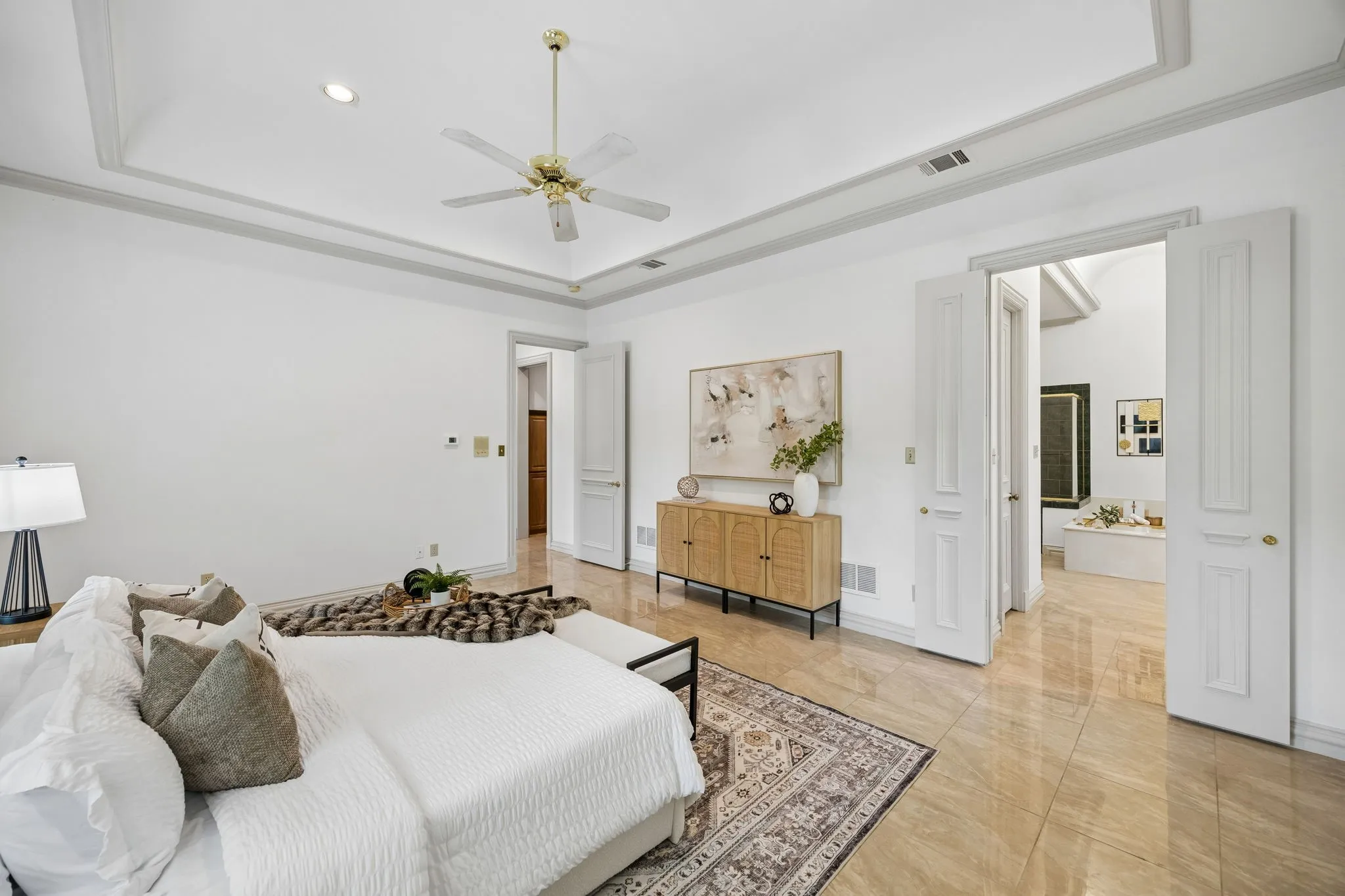 Spacious room featuring tray ceilings with crown molding, recessed lighting, and a ceiling fan