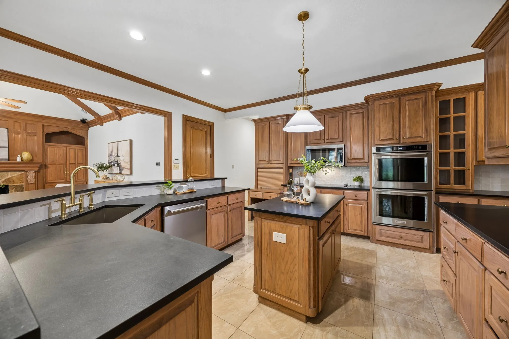 Kitchen featuring extensive wood cabinetry, dark countertops, a central island, and stainless steel double ovens