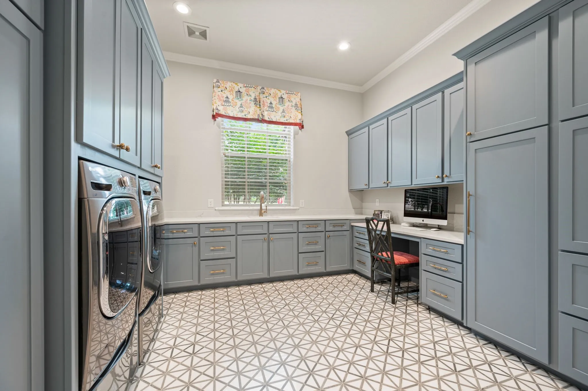 Laundry day is more pleasant in this oversized utility room  which was updated with cheery floor tiles & soft blue cabinetry!