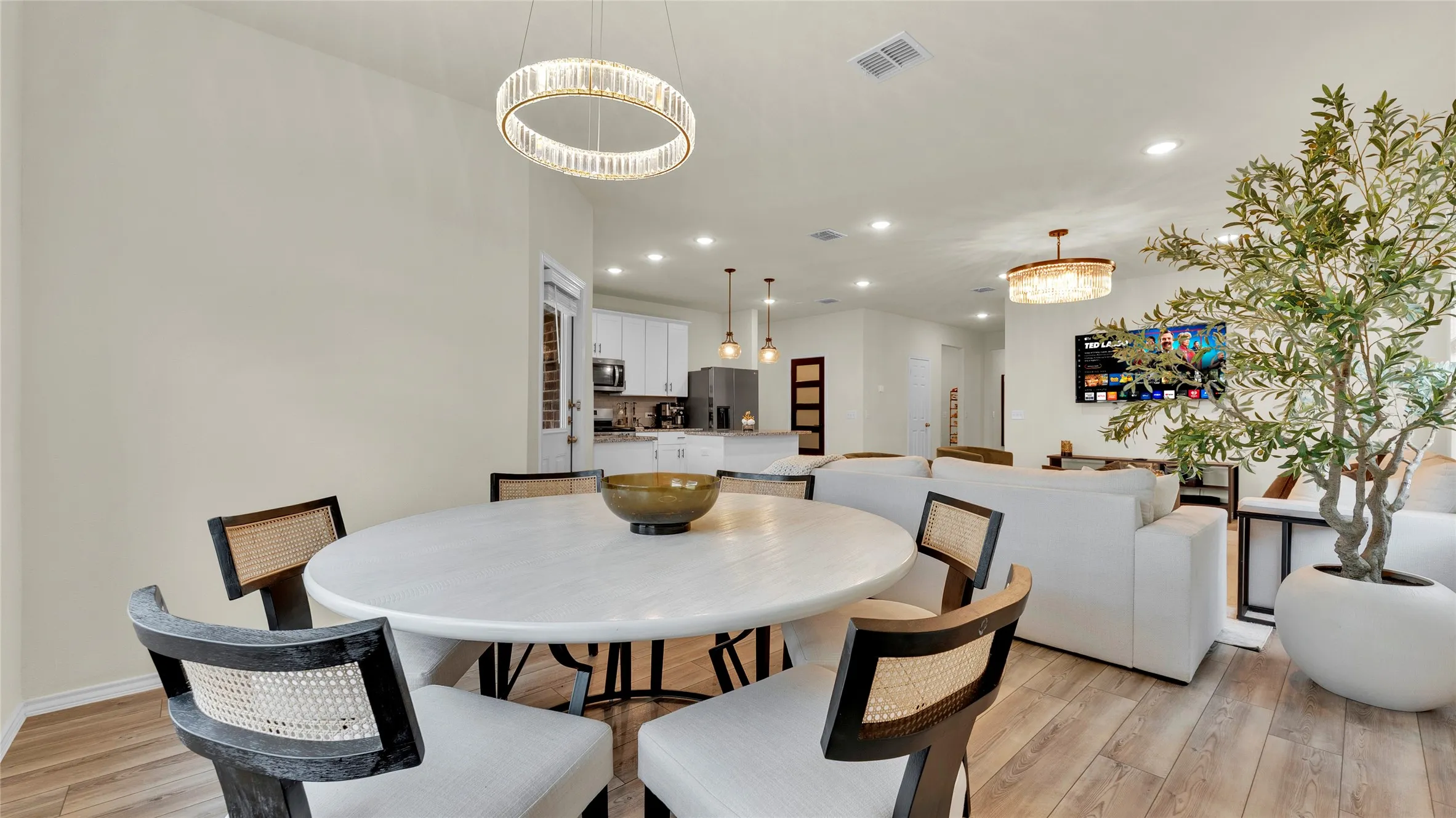 Open-concept living area featuring wood-finish flooring, recessed lighting, and a modern chandelier