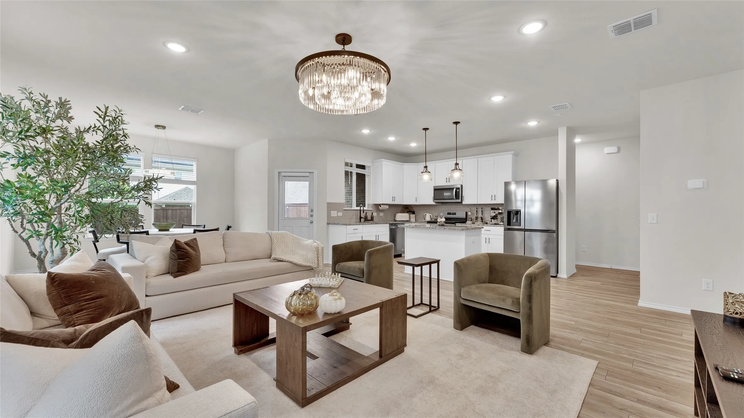 Open-concept living space featuring a contemporary chandelier, recessed lighting, and wood-finish flooring