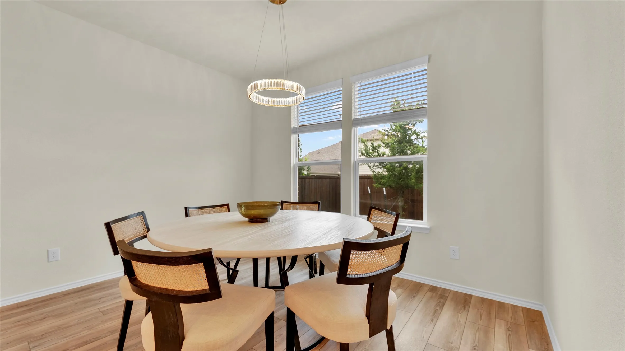 Dining area featuring light wood-finish flooring, neutral wall tones, and a modern circular chandelier