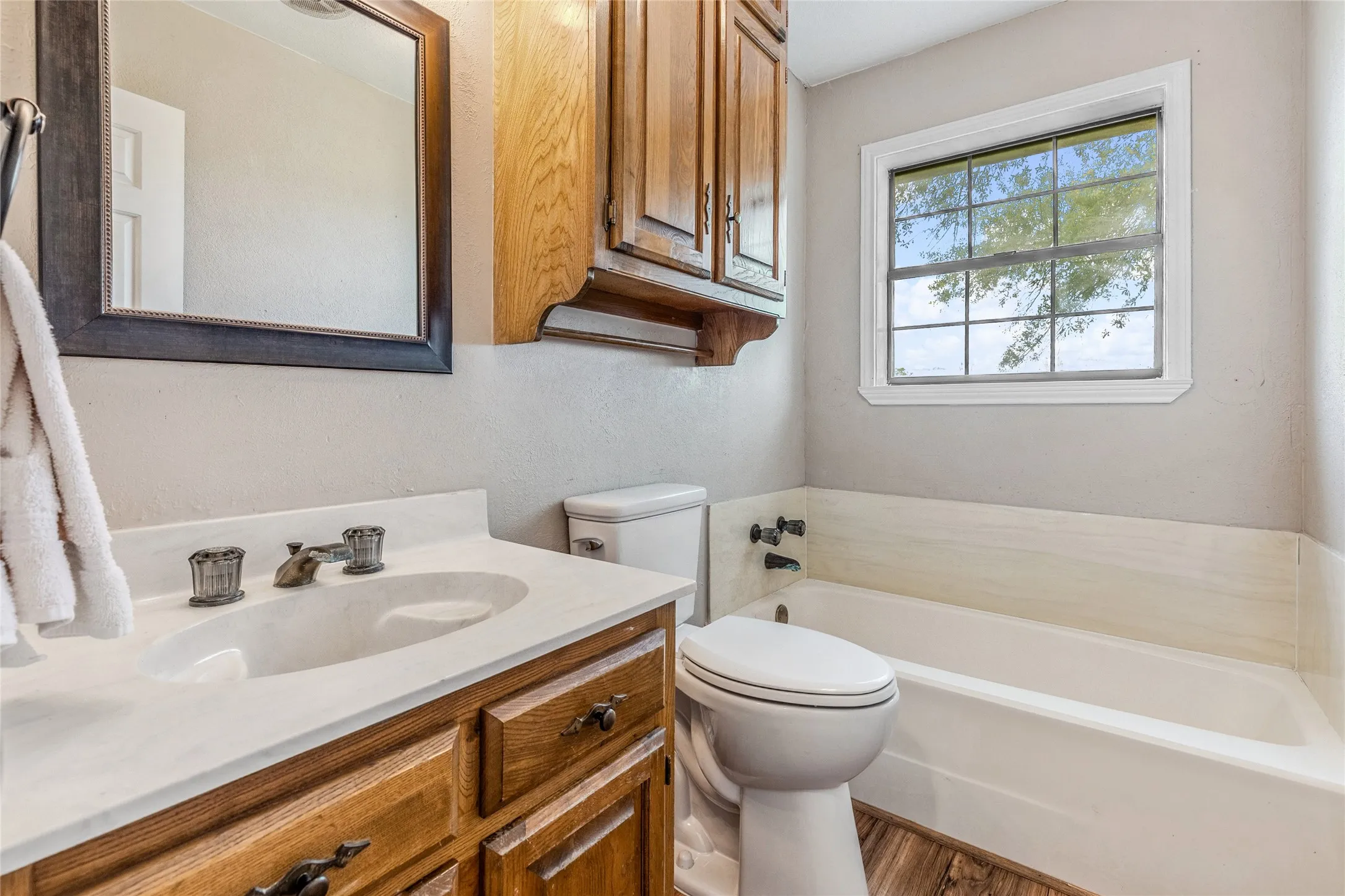 Bathroom featuring a wood-finish vanity with an integrated sink and a framed mirror