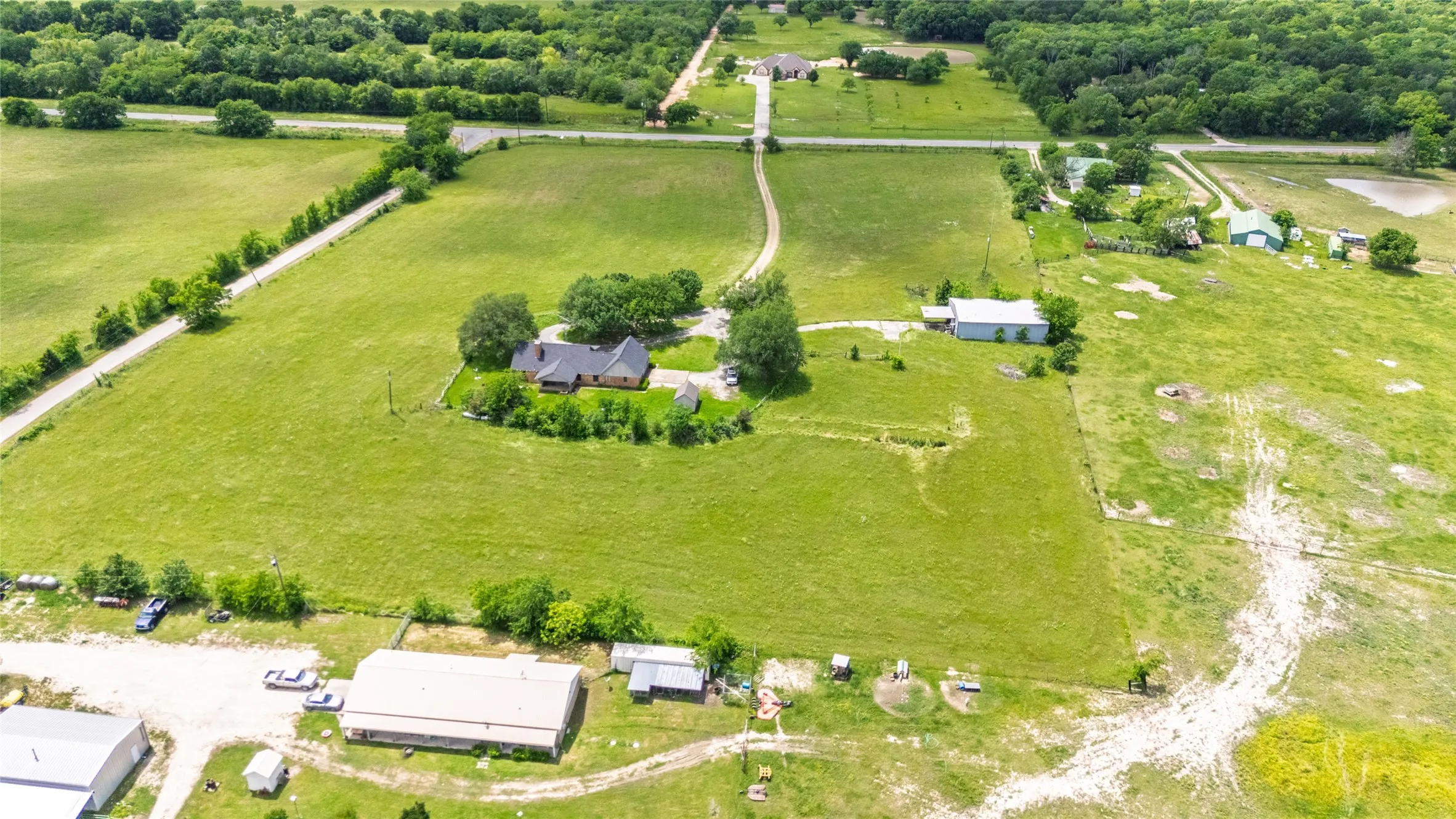 Expansive property featuring a main residence with a dark shingle roof, a detached garage, multiple outbuildings, and a​​‌​​​​‌​​‌‌​‌‌​​​‌‌​‌​‌​‌​​​‌​​ pond