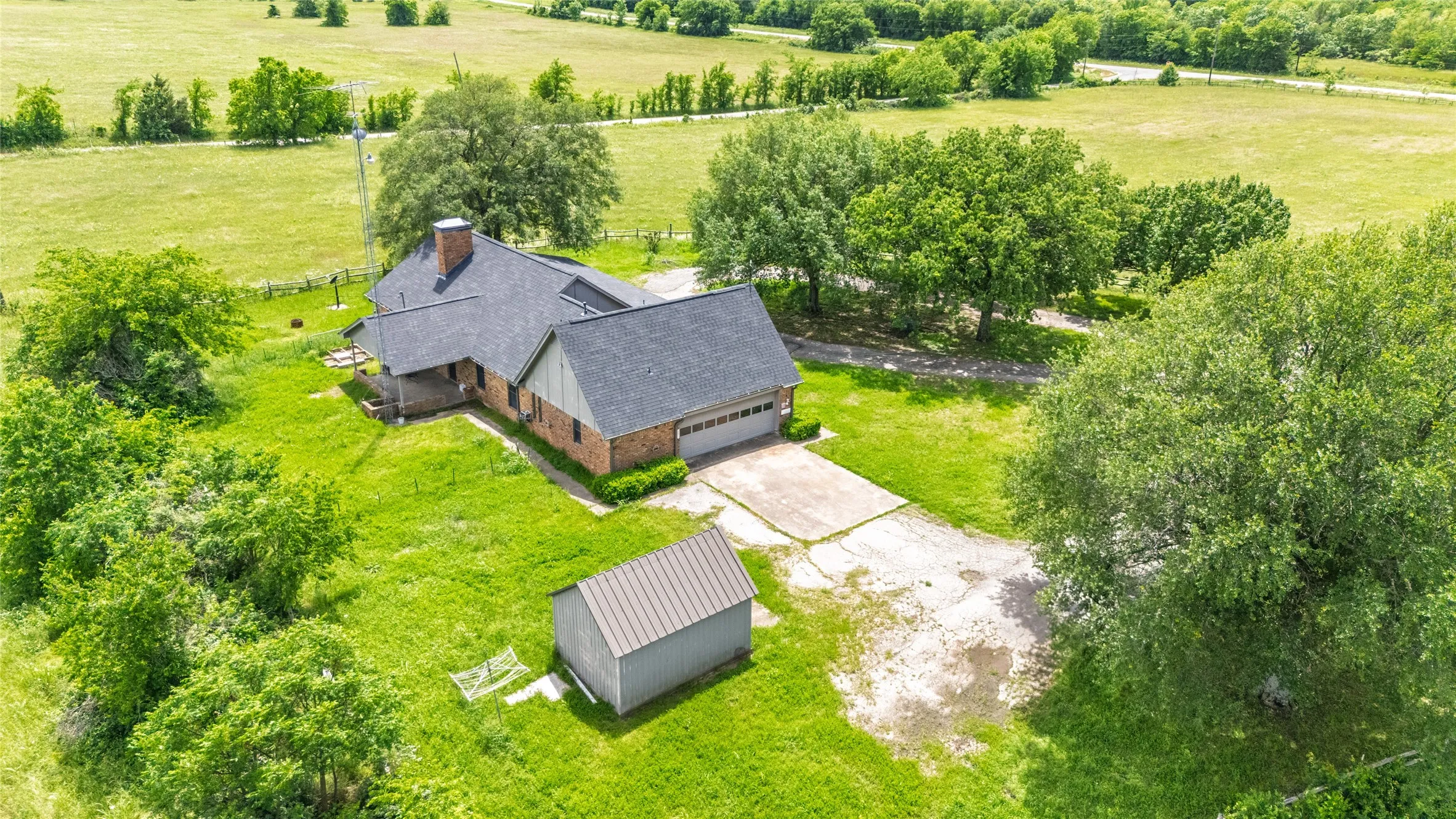 Brick residence featuring an attached garage, a dark shingle roof, and a prominent chimney