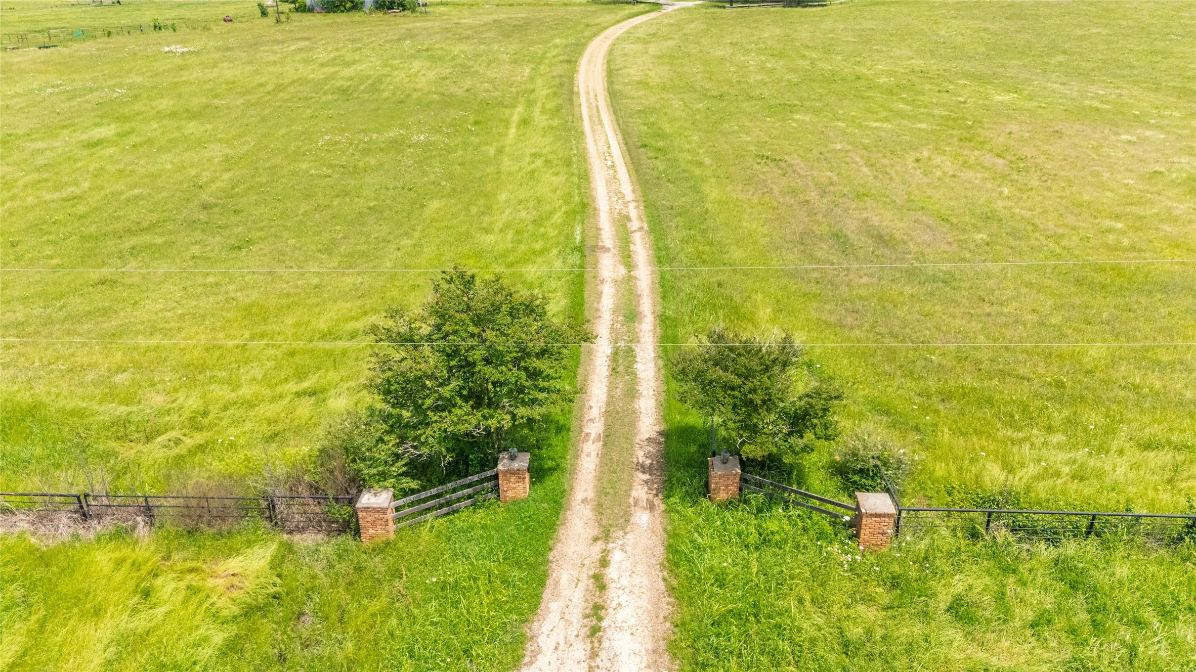 Expansive green acreage featuring a winding dirt road entrance