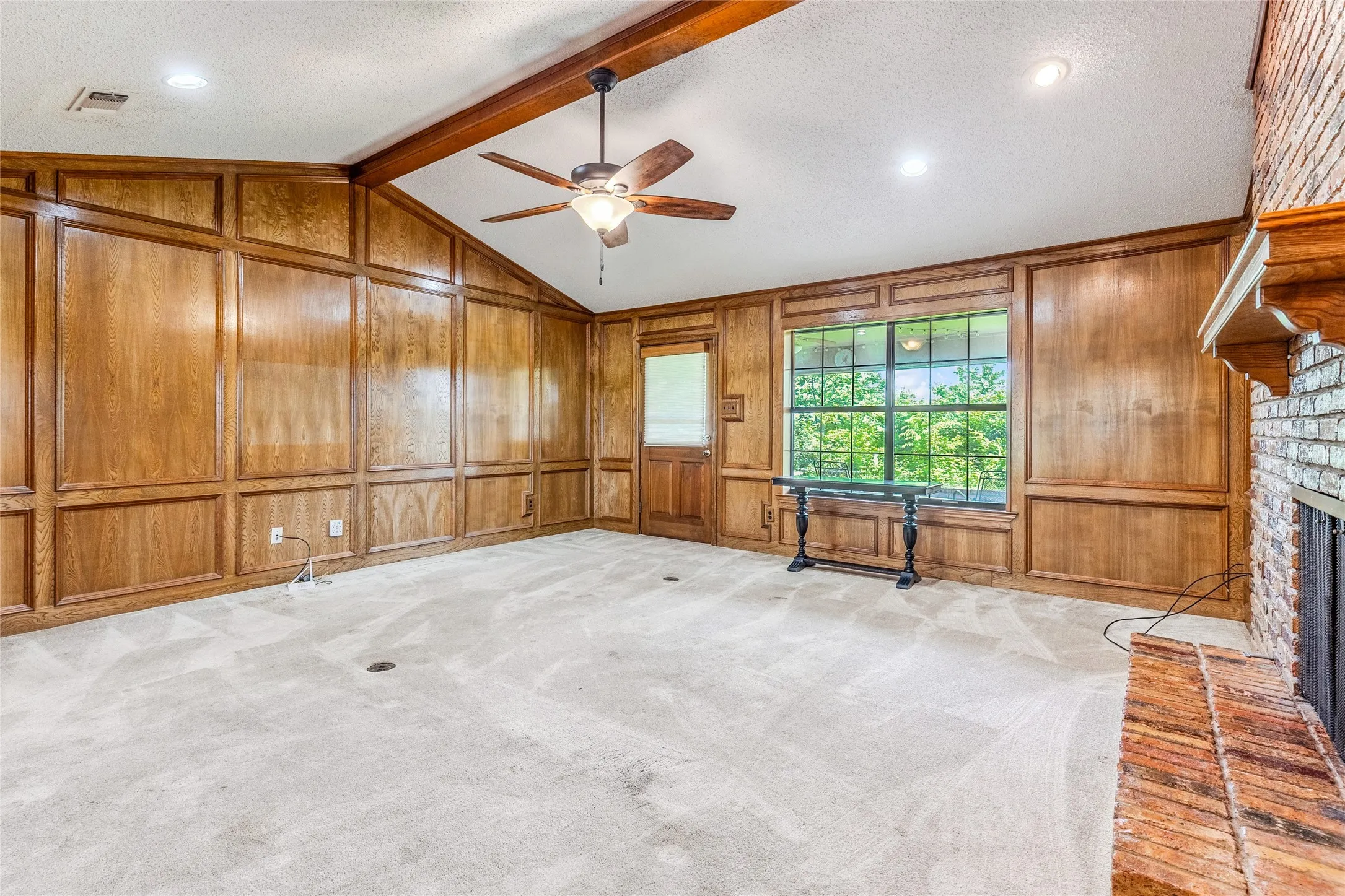 Living area featuring extensive wood paneling and a vaulted ceiling with exposed wood beams