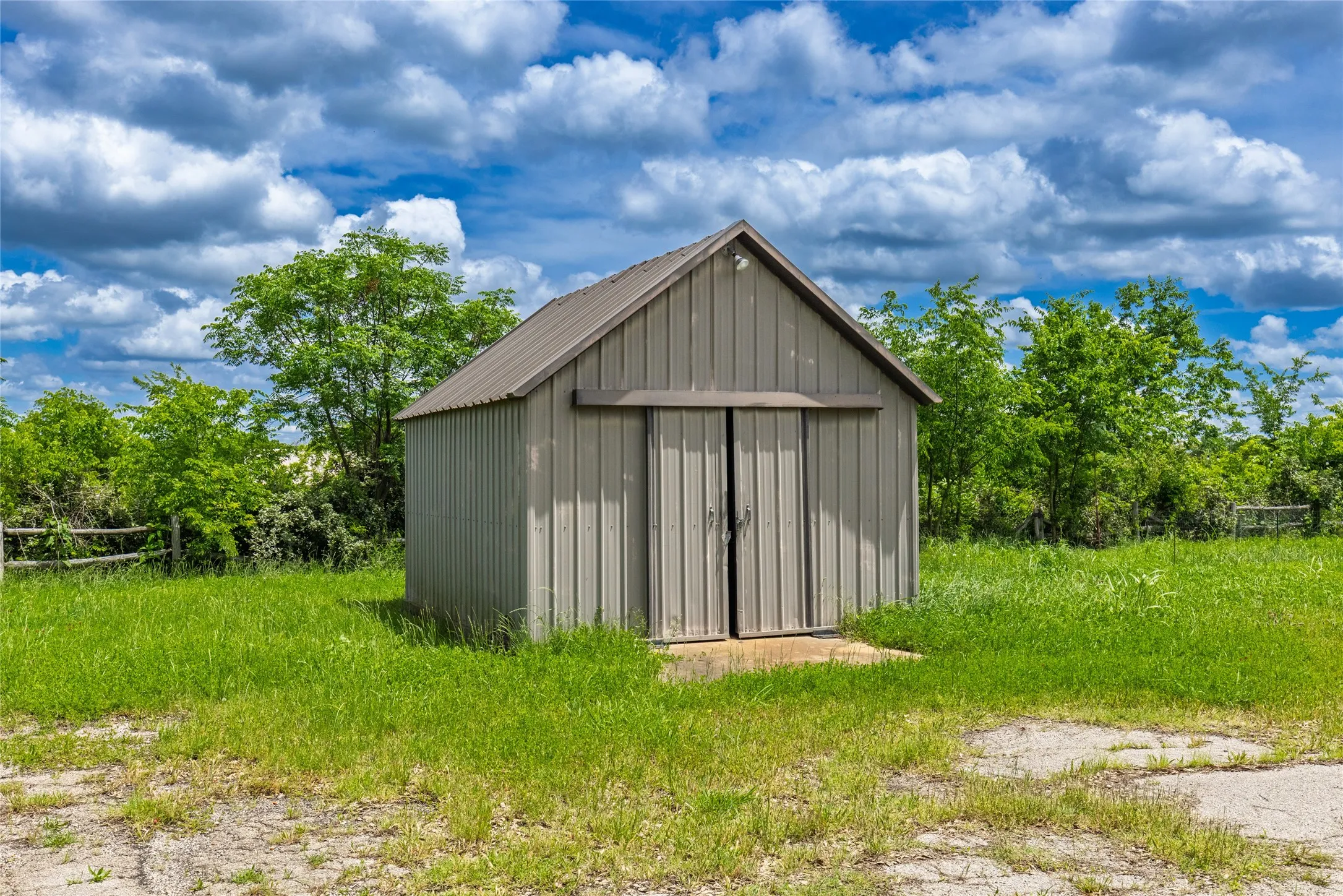 Freestanding utility building featuring corrugated metal siding and a pitched metal roof