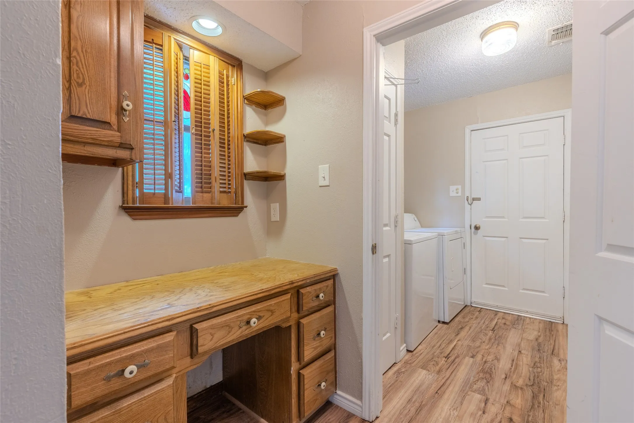 Wood-finish flooring throughout, featuring a built-in wooden desk with drawers and an upper cabinet