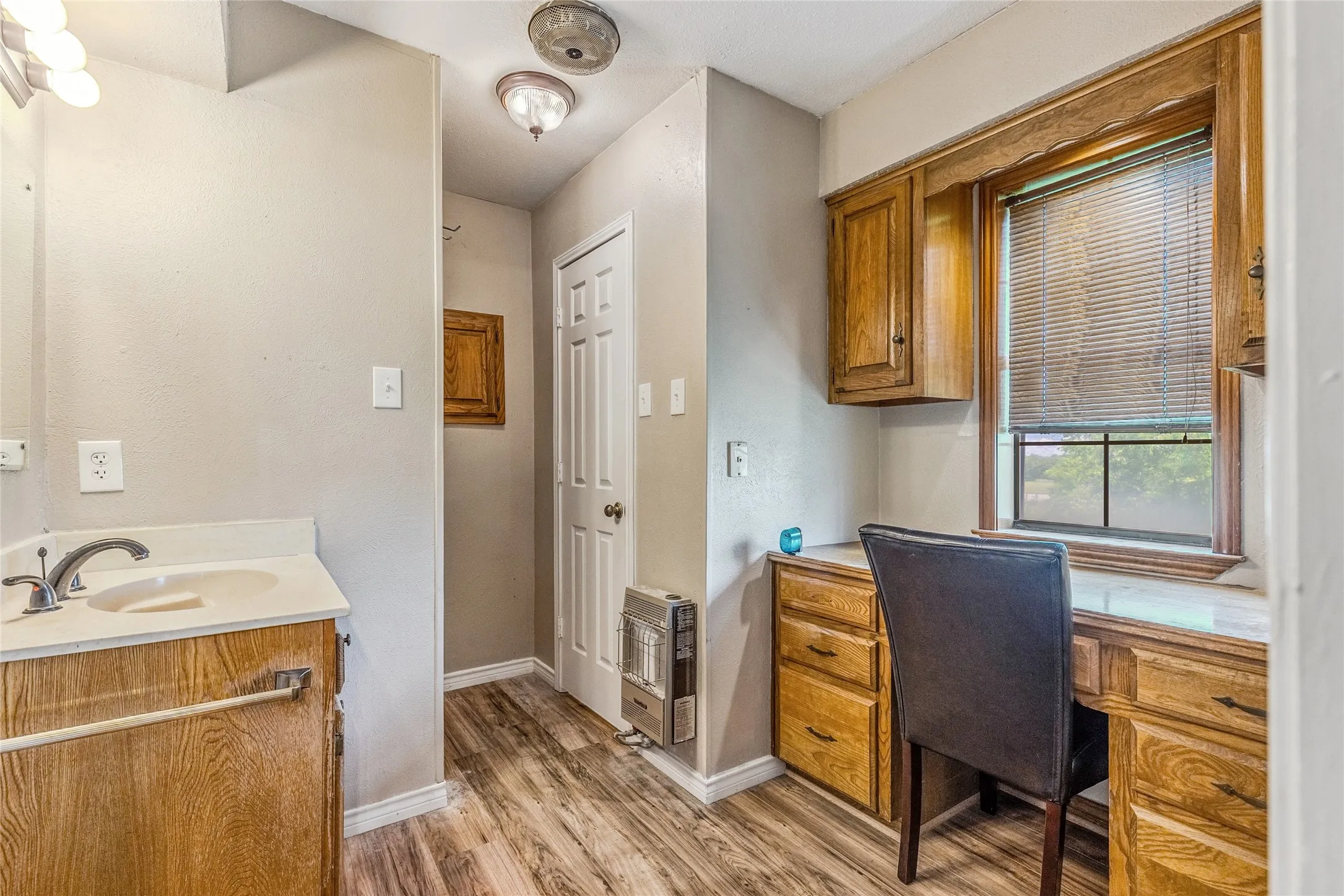 Integrated vanity with composite countertop and undermount sink, wood-finish flooring, and built-in desk area with wood cabinetry