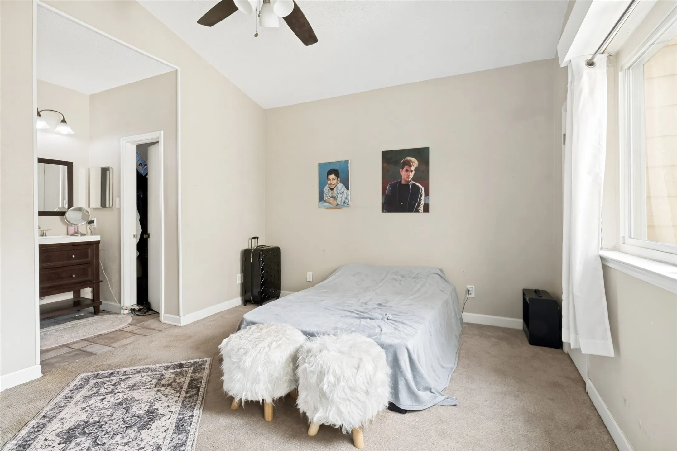 Carpeted sleeping area featuring a vaulted ceiling and a ceiling fan with light fixture