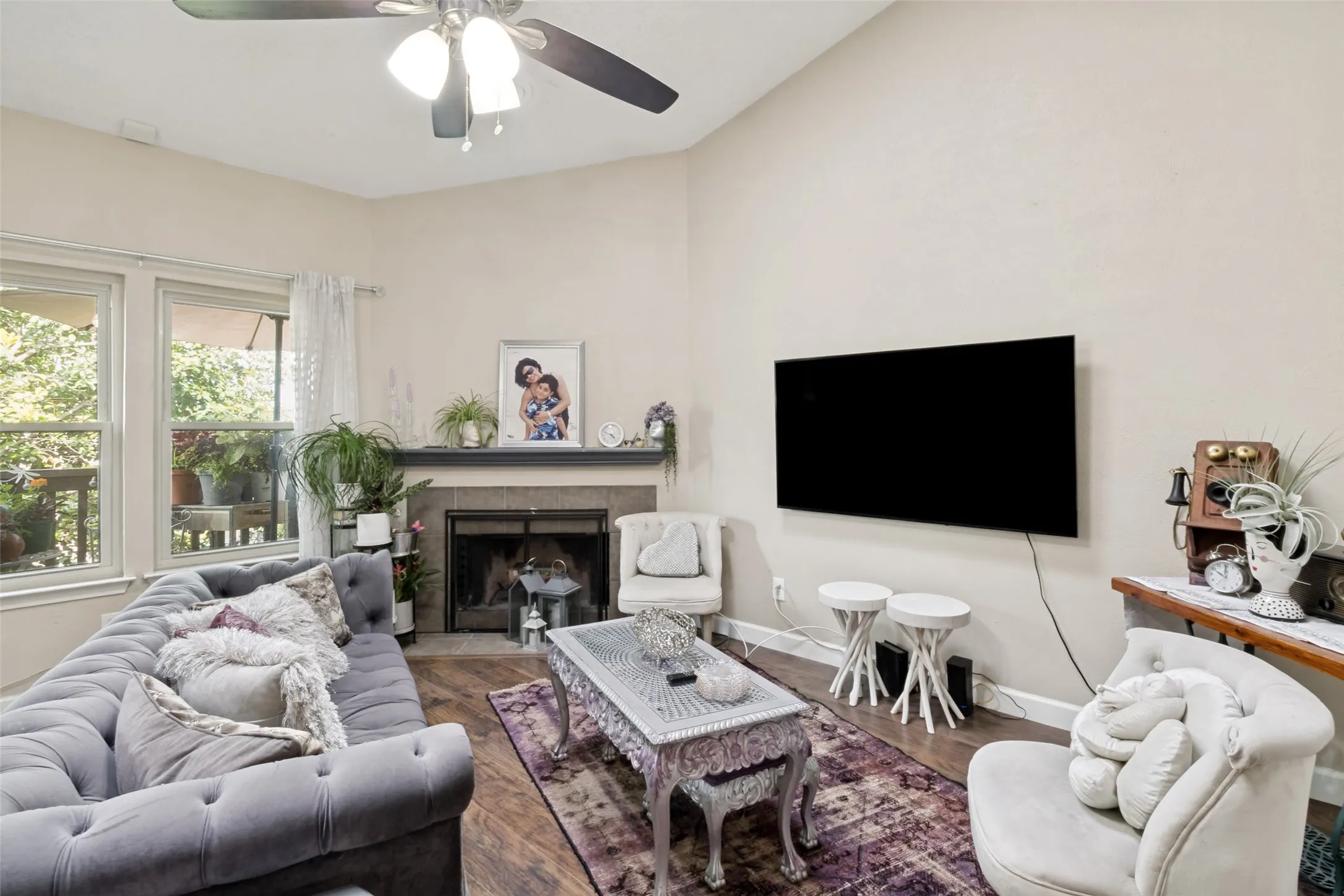 Vaulted ceiling living area featuring wood-finish flooring, a ceiling fan, and large windows