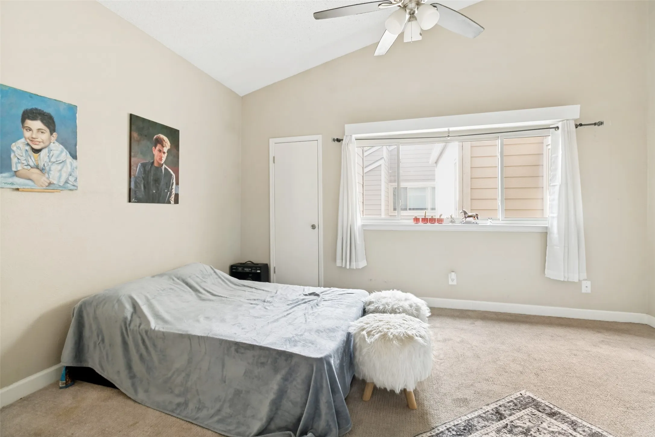 Room featuring vaulted ceilings, carpet flooring, a ceiling fan, and a window with white trim