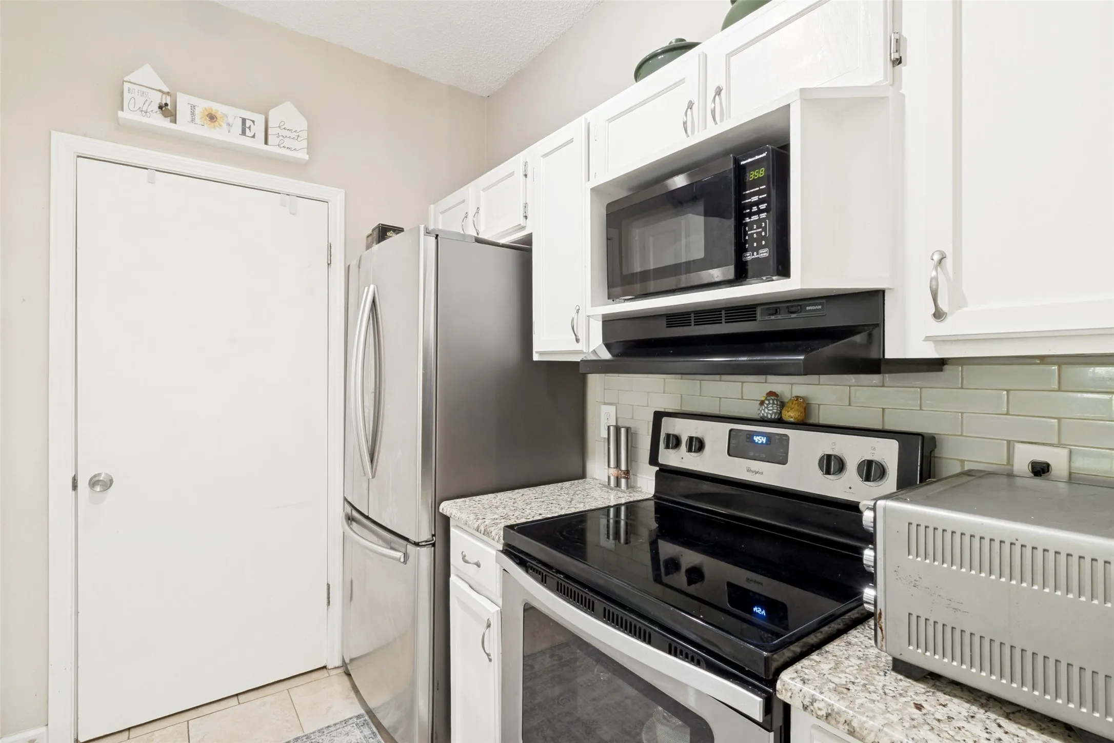 Kitchen featuring white cabinetry, light-toned countertops, and a subway tile backsplash