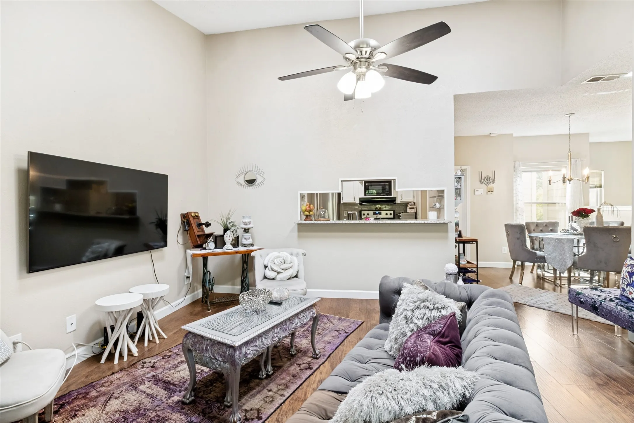 Spacious living area featuring high vaulted ceilings, wood-finish flooring, and an open concept layout with a kitchen pass-through