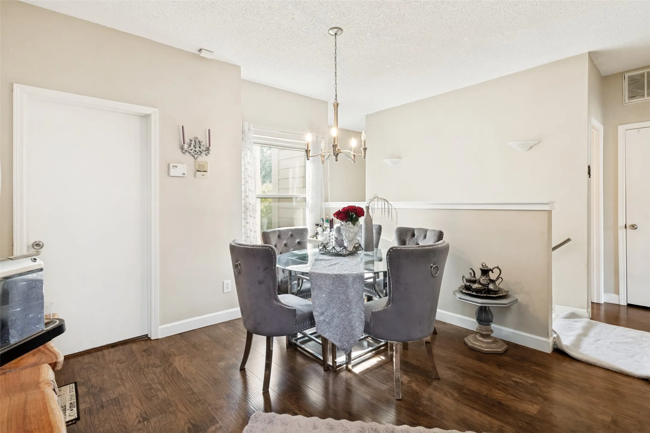 Dining area featuring wood-finish flooring, a contemporary chandelier, neutral wall tones, a large window, and a half-wall partition