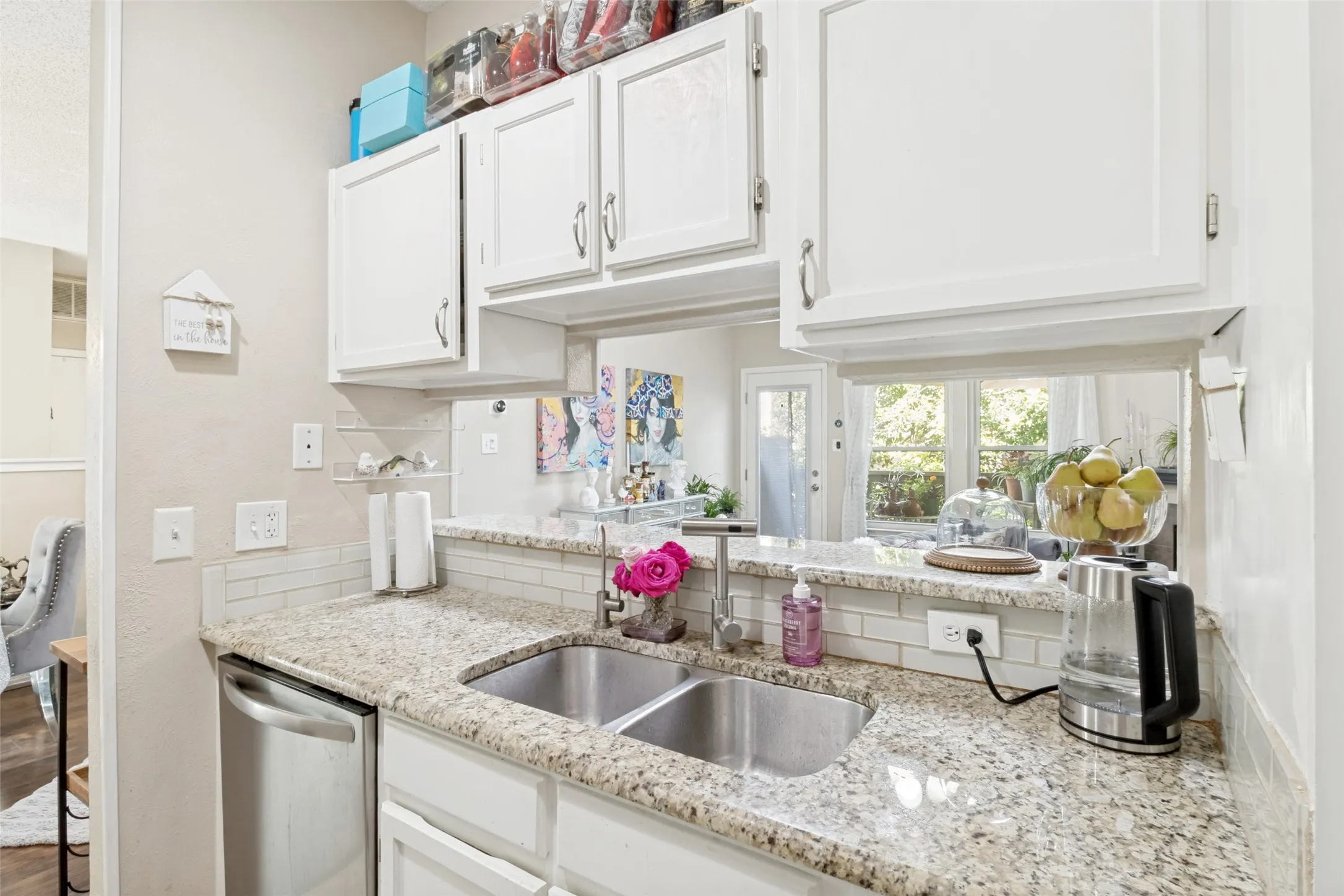 Kitchen featuring white cabinetry, granite-finish countertops, subway tile backsplash, and a stainless steel double basin sink
