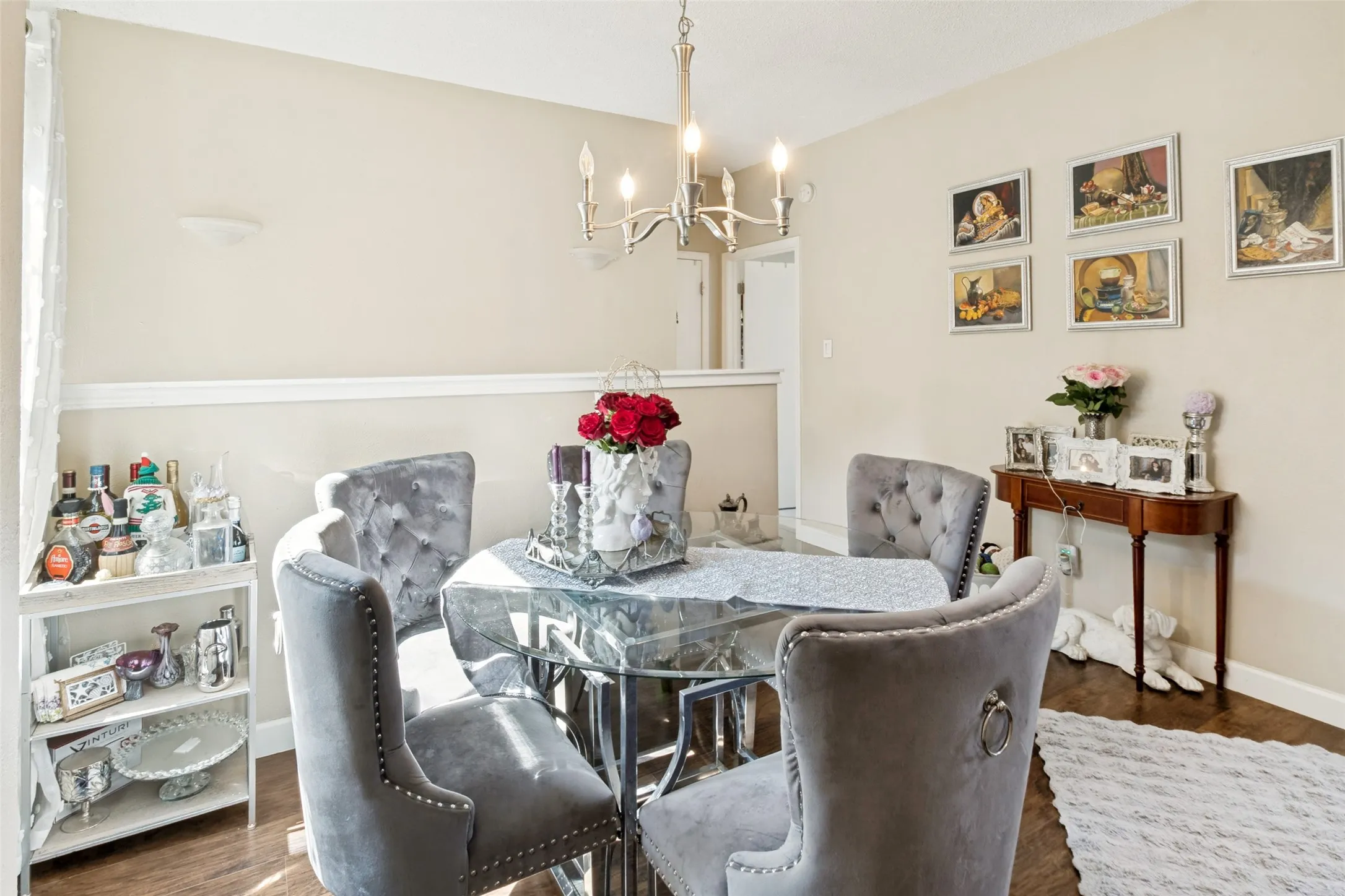 Dining area featuring rich wood-finish flooring, a contemporary chandelier, and a low architectural divider