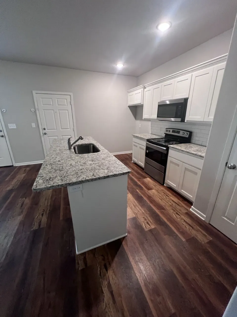 Kitchen island featuring a stainless steel sink and light-toned countertop