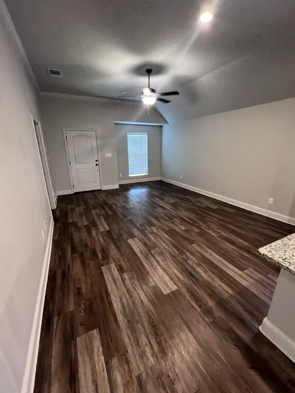 Spacious living area featuring wood-finish flooring, a vaulted ceiling, recessed lighting, and a ceiling fan