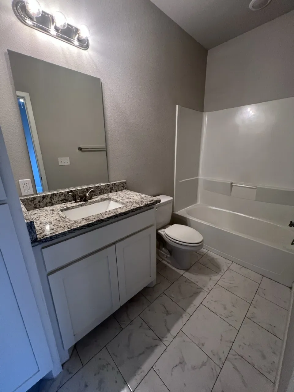 Bathroom featuring a white vanity with a granite-style countertop, undermount sink, and chrome faucet