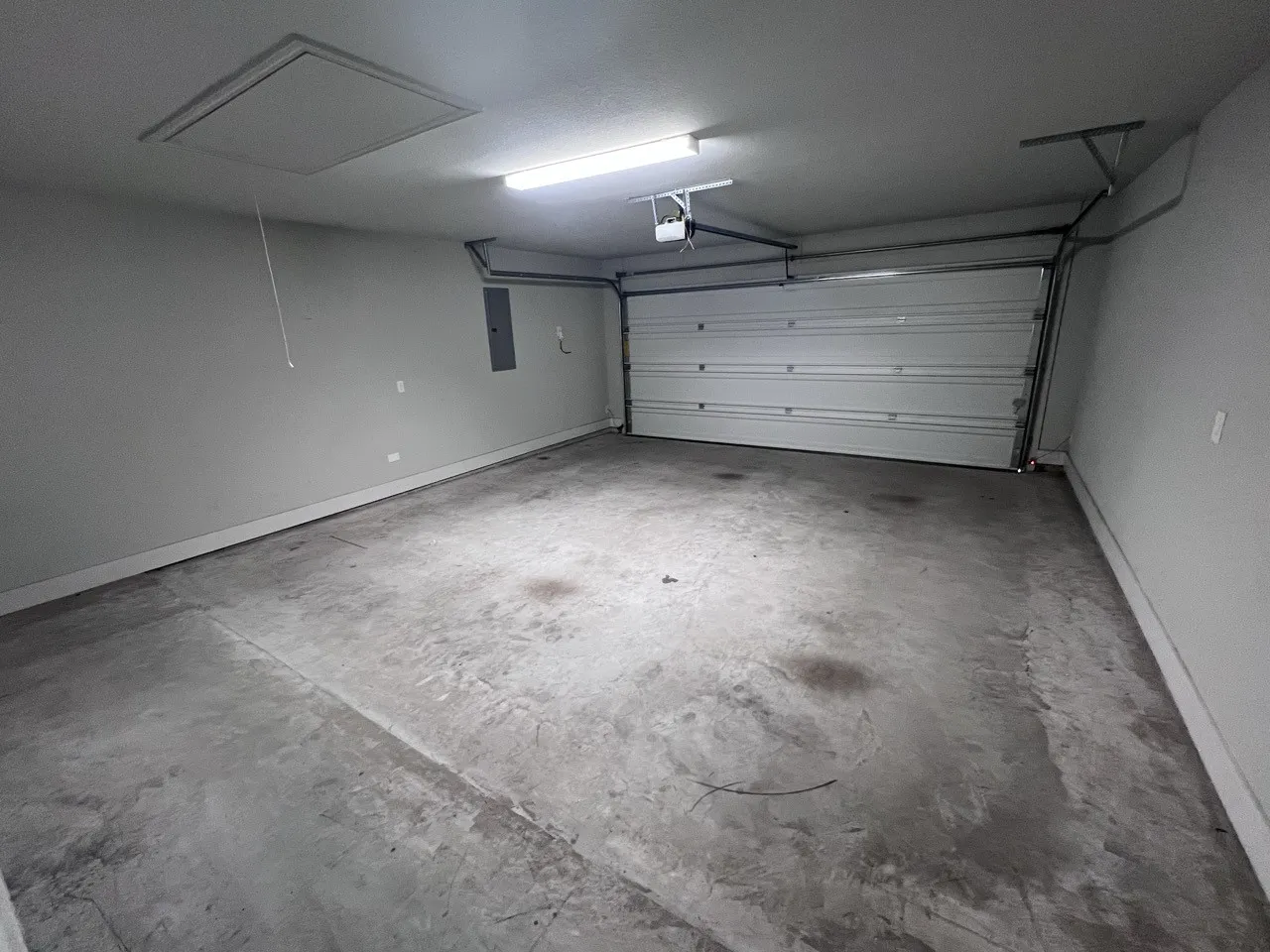 Spacious garage with a sectional garage door, exposed ceiling joists, and a concrete floor