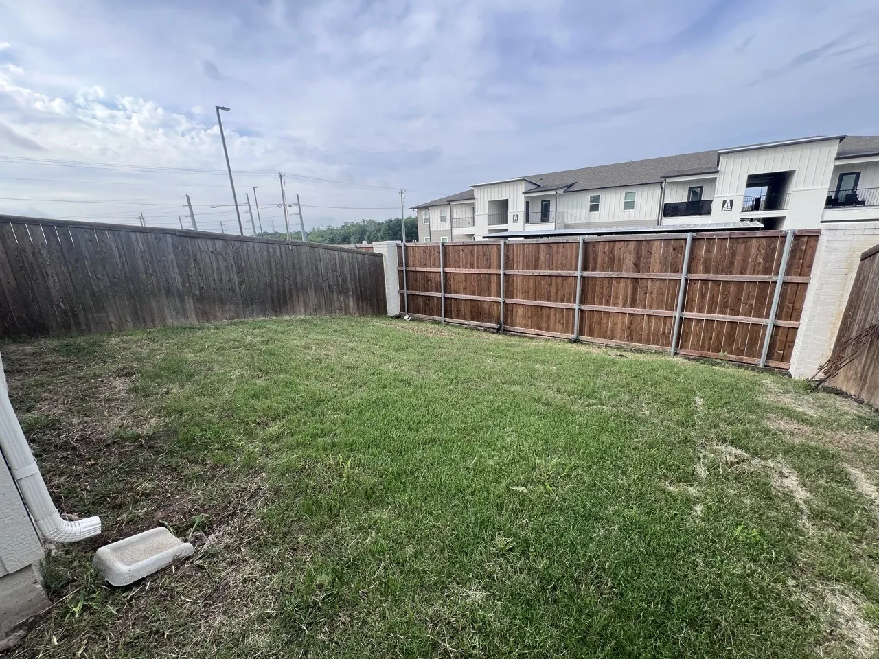 Expansive backyard featuring a combination of wood fencing and brick retaining walls, offering privacy
