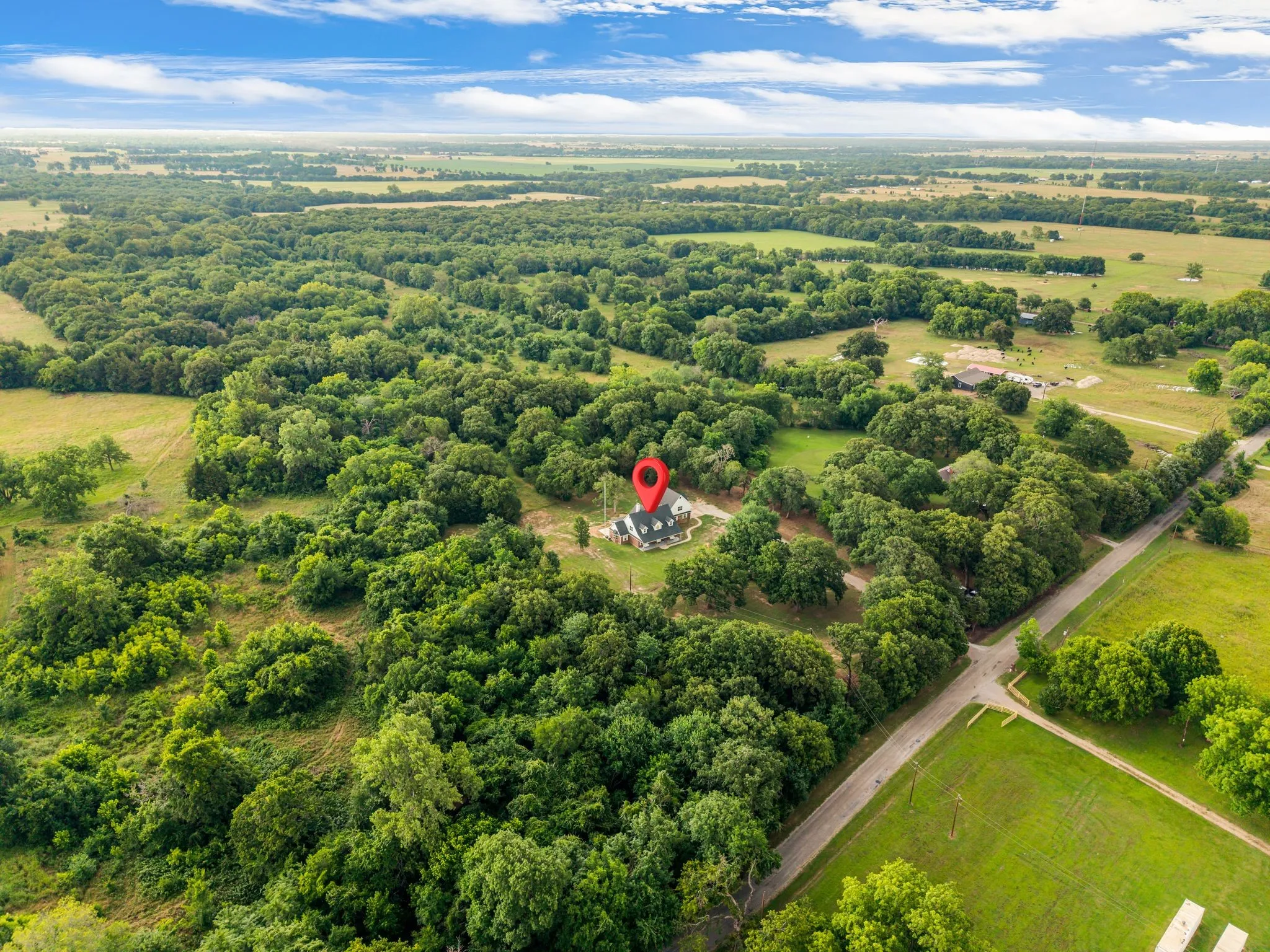 Expansive aerial view showcasing a property situated amidst abundant mature trees and natural greenery