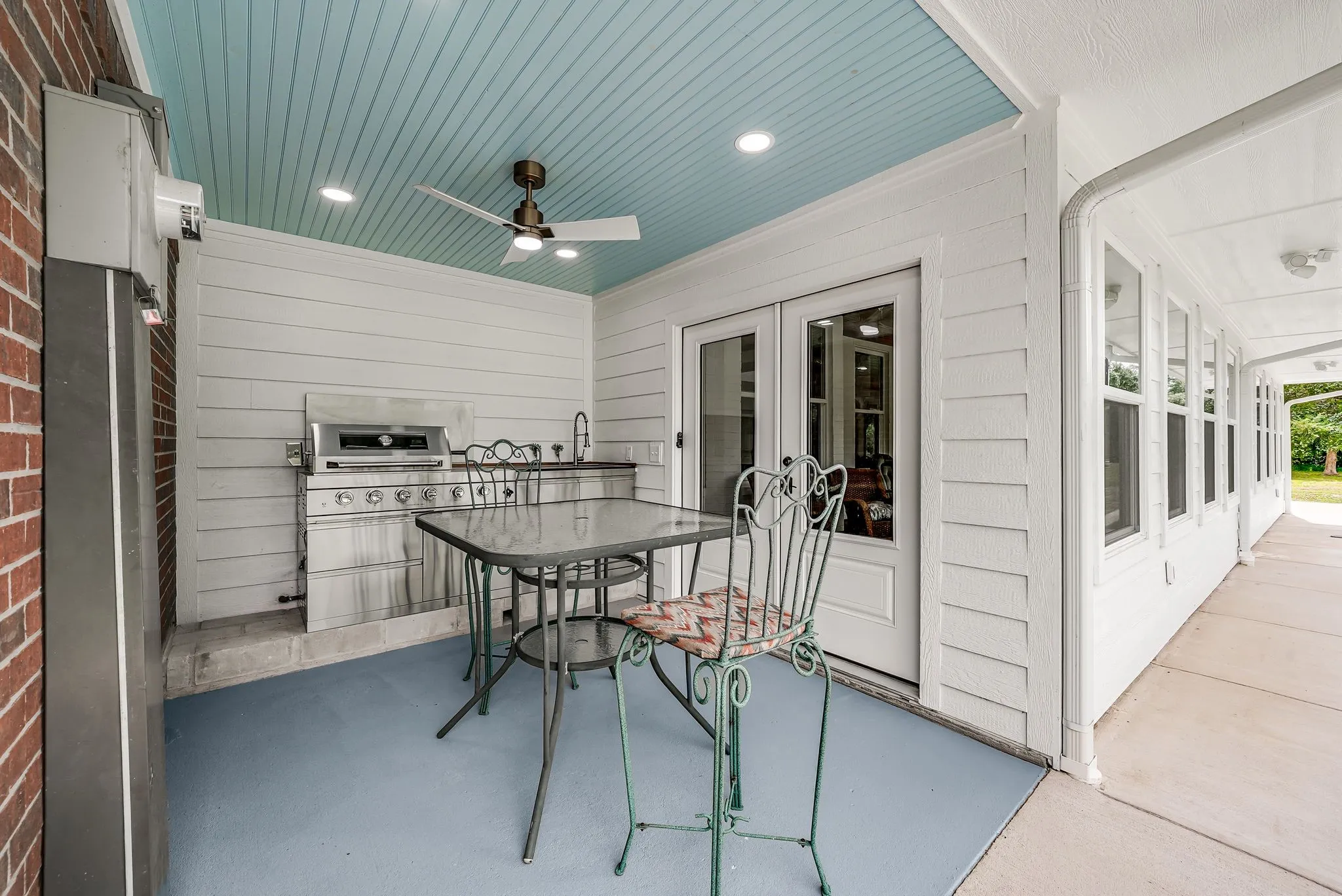 Outdoor living area with a built-in stainless steel grill, integrated sink, and recessed lighting
