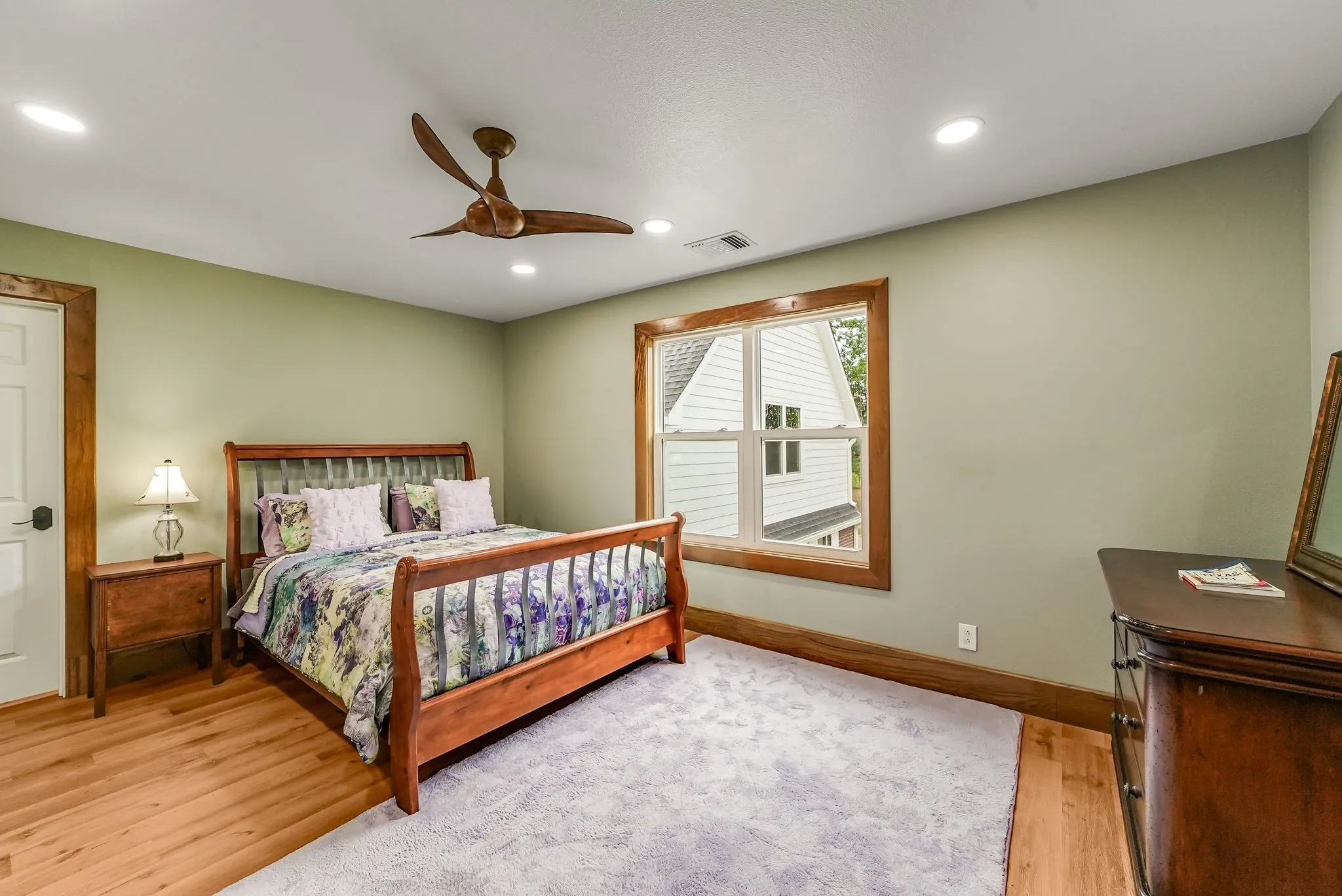 Bedroom #4 on second floor featuring wood-finish flooring, a contemporary ceiling fan, recessed lighting, a large window with natural wood trim, and a paneled door with matching wood trim