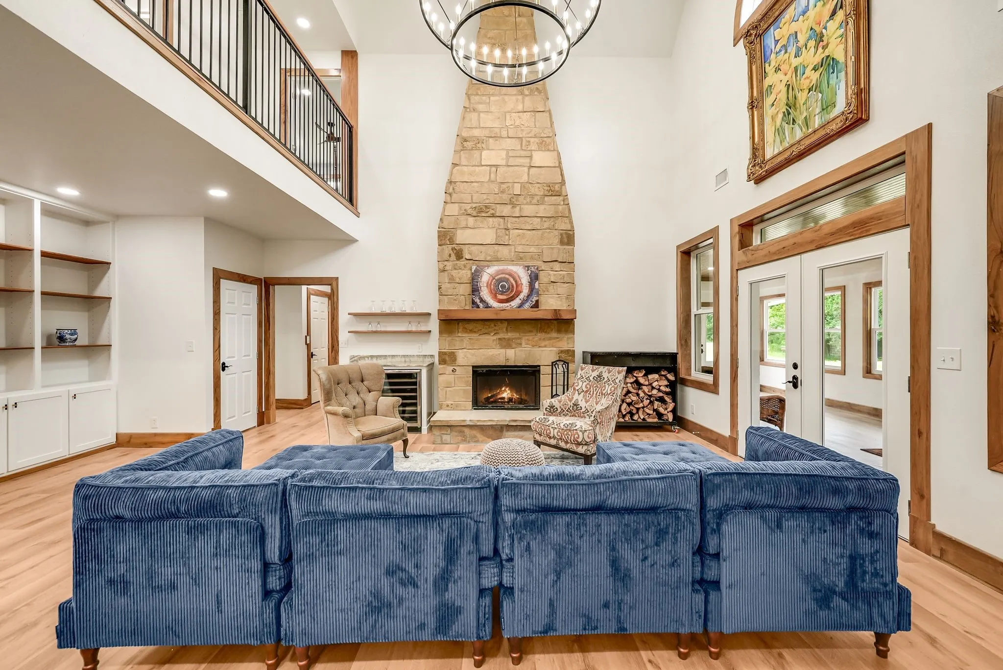 Vaulted living space featuring a stone fireplace with a wood mantel, built-in shelving, wood-finish flooring, and a second-story balcony
