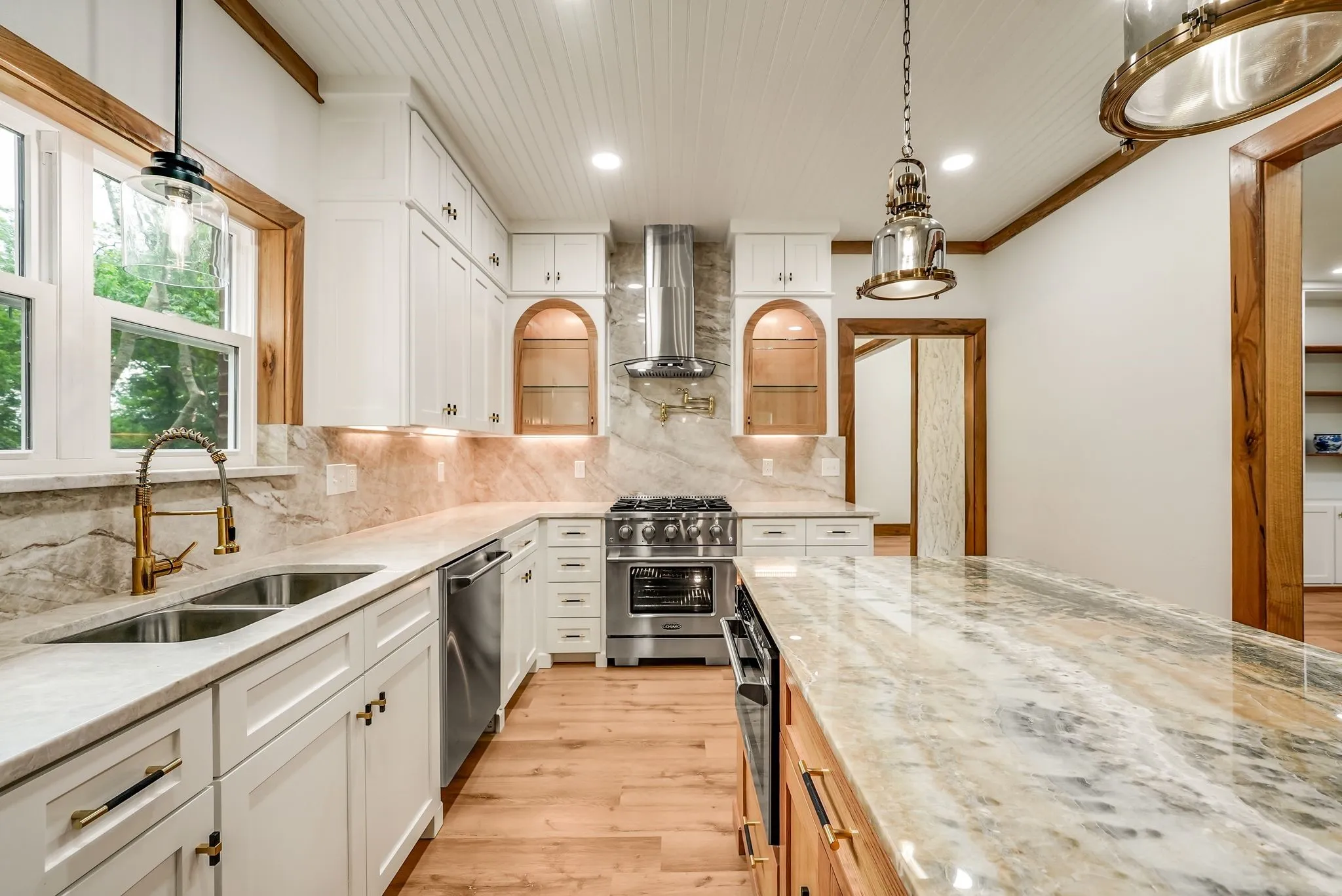 Gourmet kitchen featuring white shaker cabinetry, patterned stone countertops, stainless steel appliances, wood-finish flooring, and a beadboard ceiling