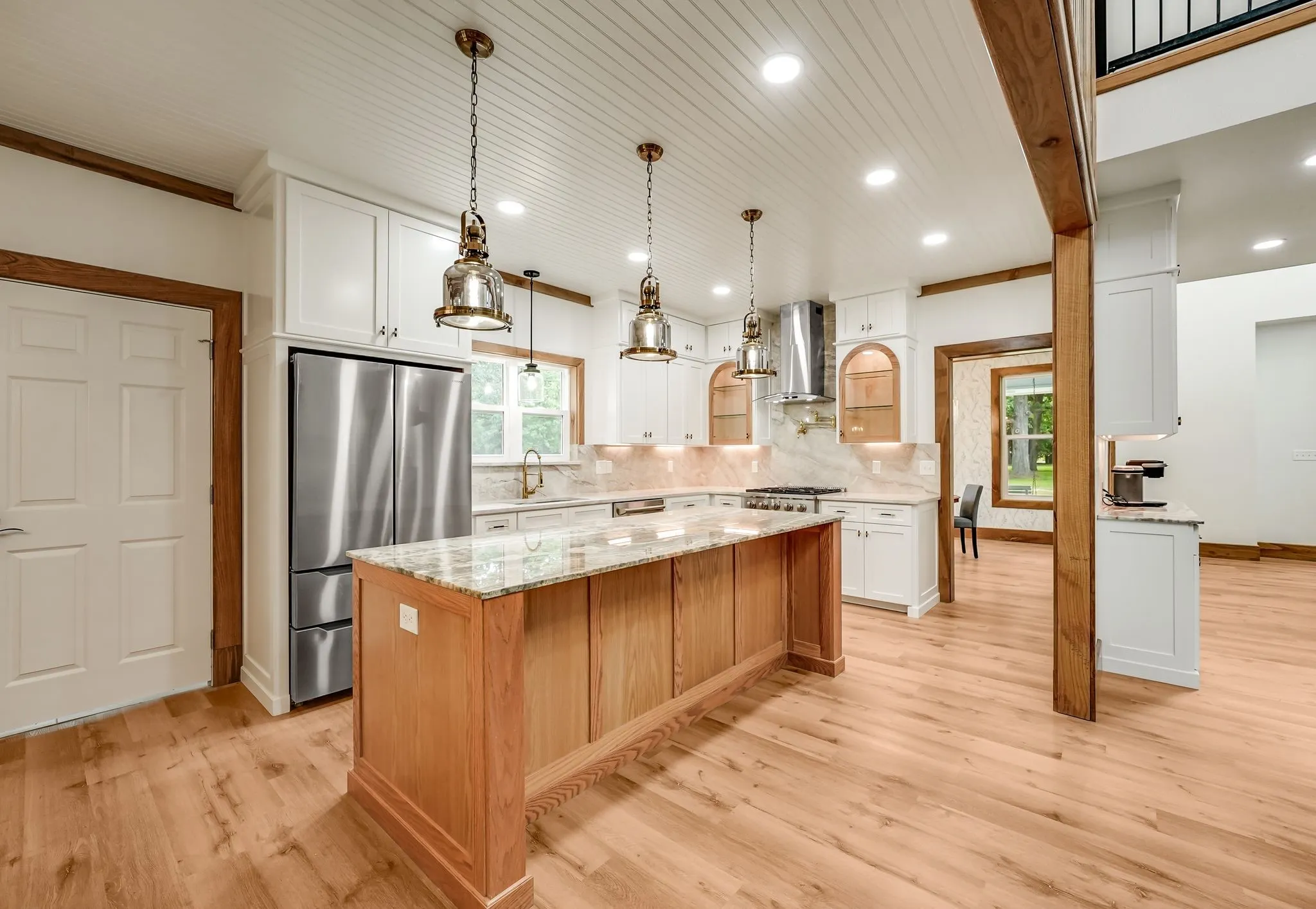 Kitchen featuring a natural wood-finish island with a light-toned countertop, stainless steel appliances, white cabinetry, and wood-finish flooring