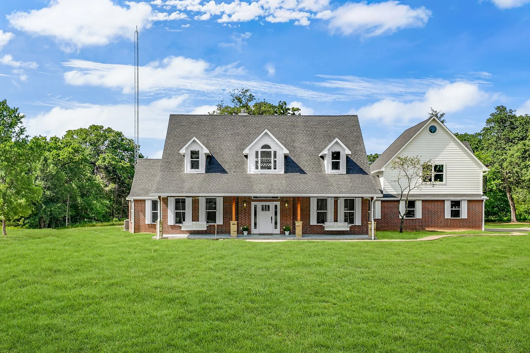 Expansive front lawn complementing a red brick and white siding exterior