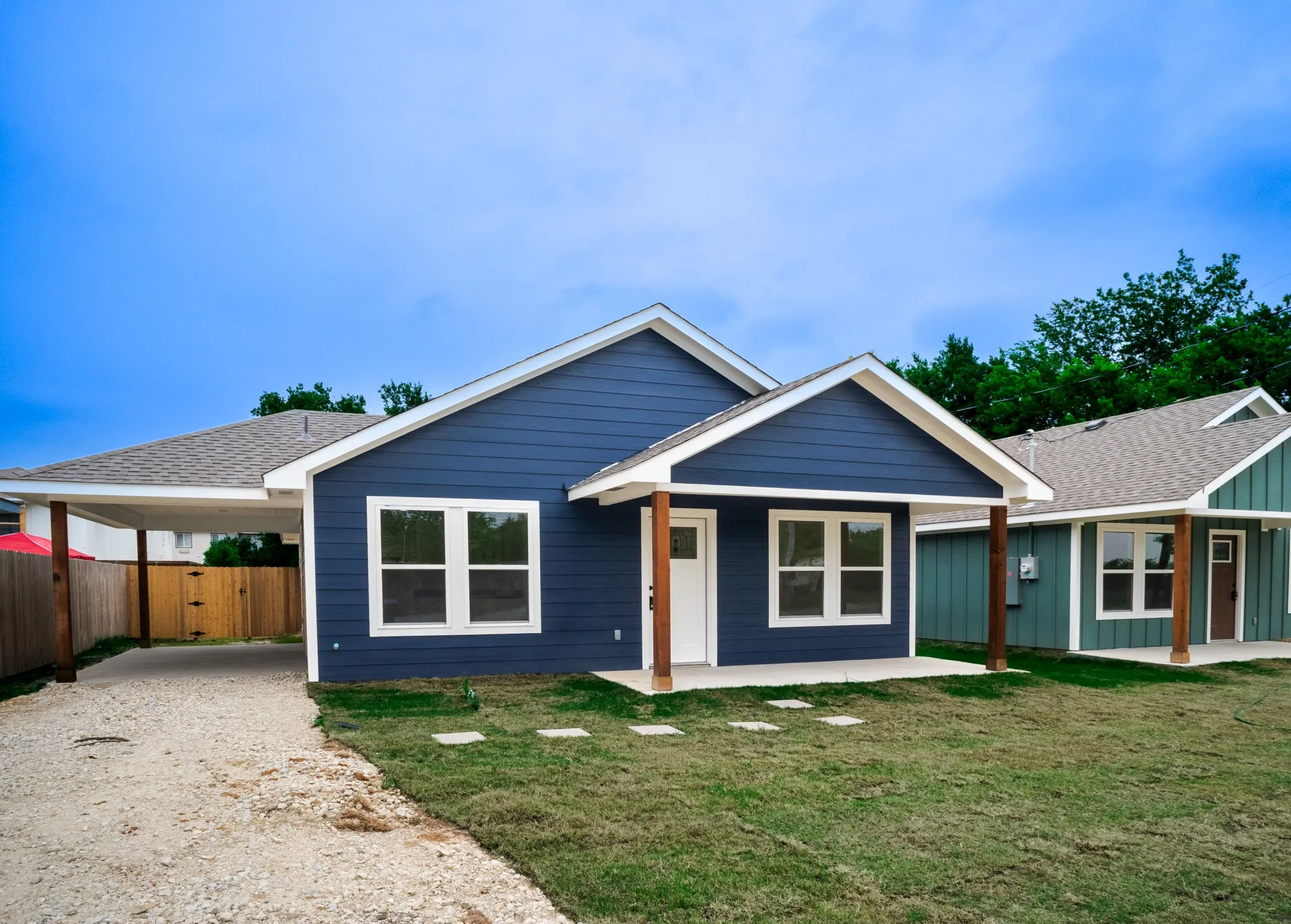 Contemporary home with a deep blue facade, white trim, and a covered carport