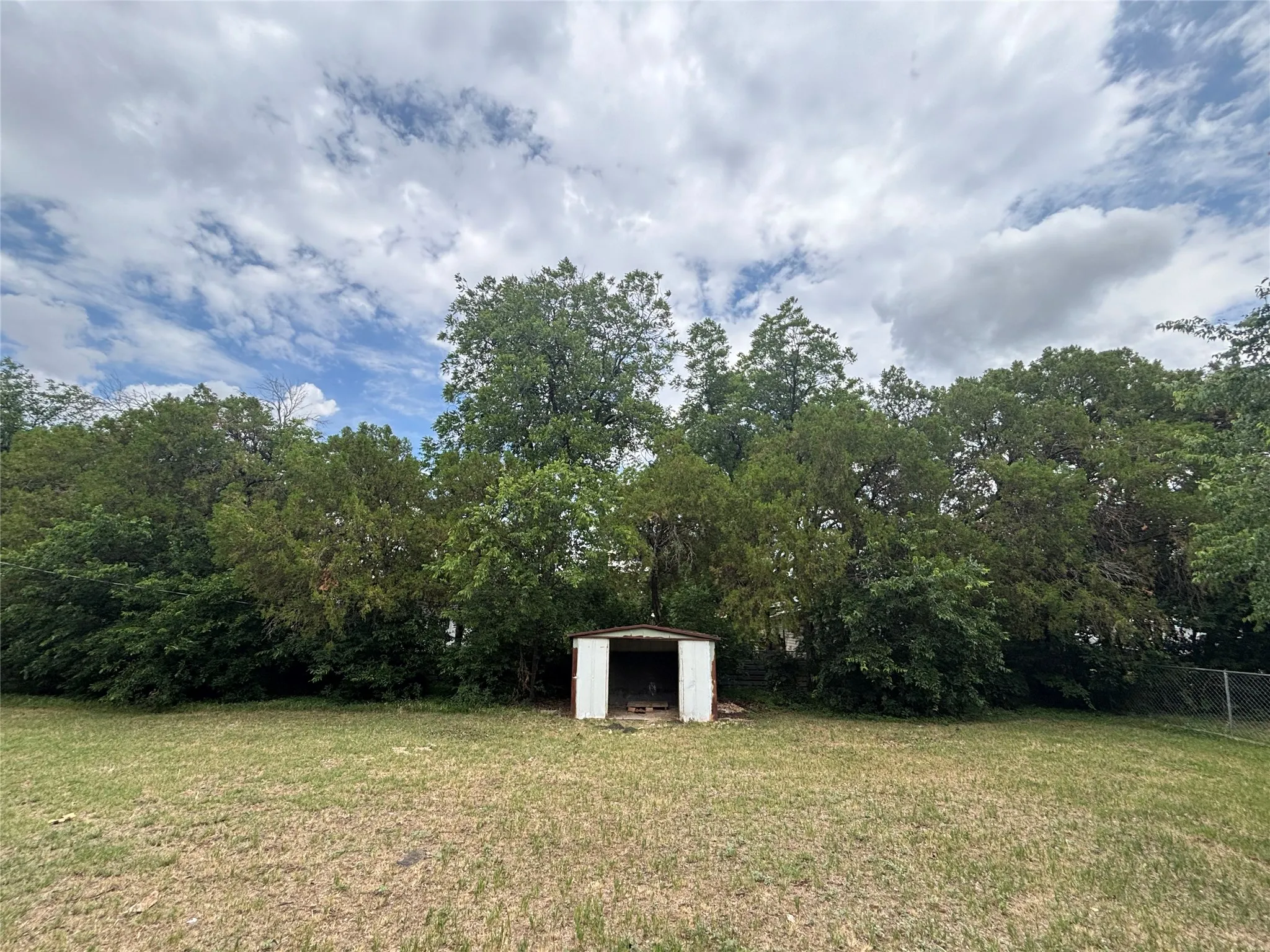 Expansive grassy area with a freestanding metal shed