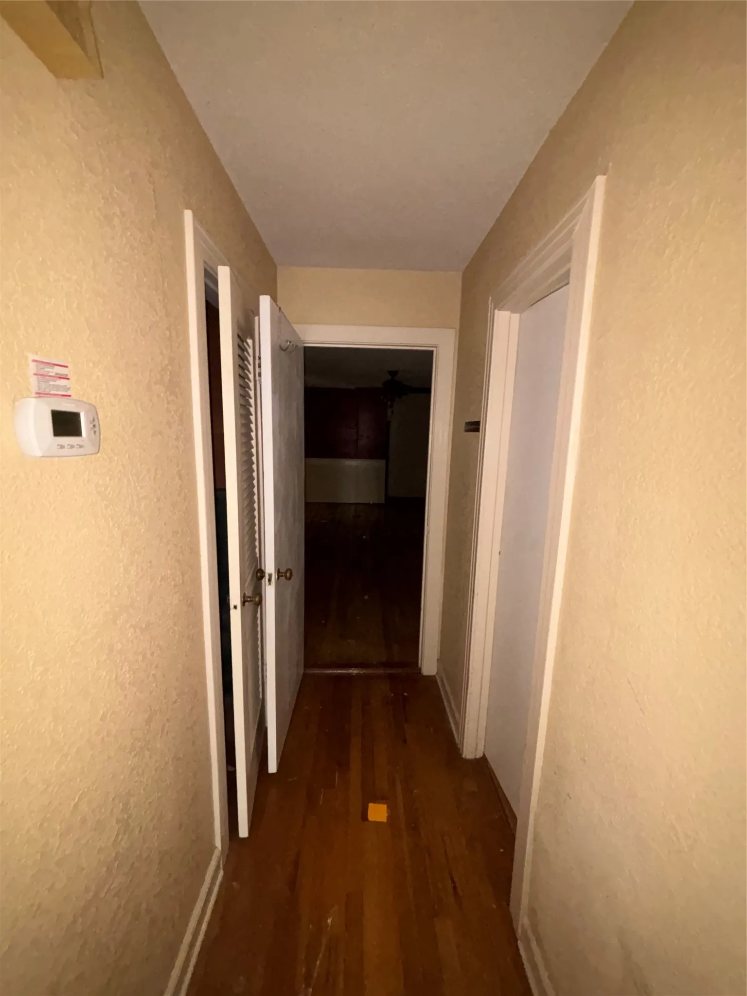 Hallway with wood-finish flooring, textured walls, and a built-in thermostat