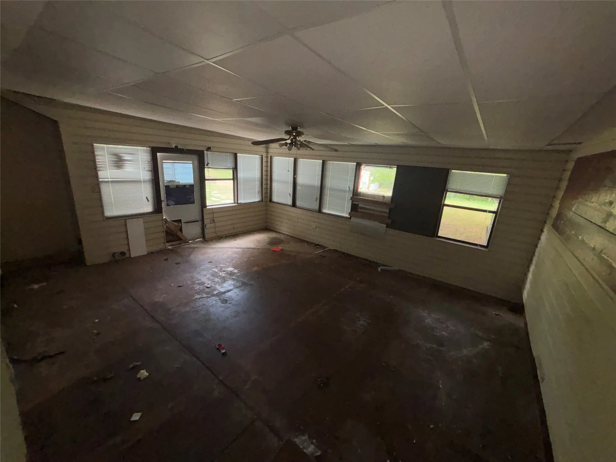 Enclosed porch featuring multiple windows, a ceiling fan, and a paneled ceiling