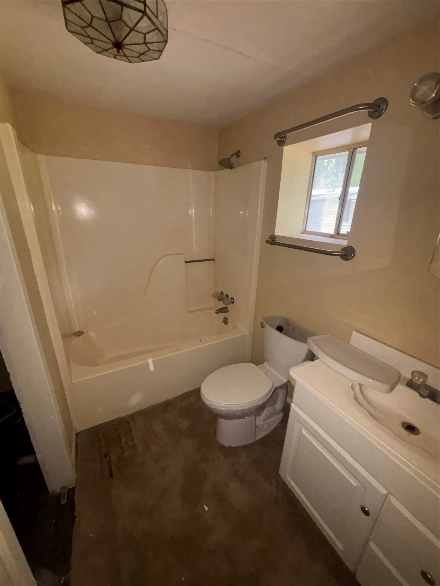 Bathroom featuring a white bathtub/shower combination, a single-pane window, and a vanity with white cabinetry and an integrated sink