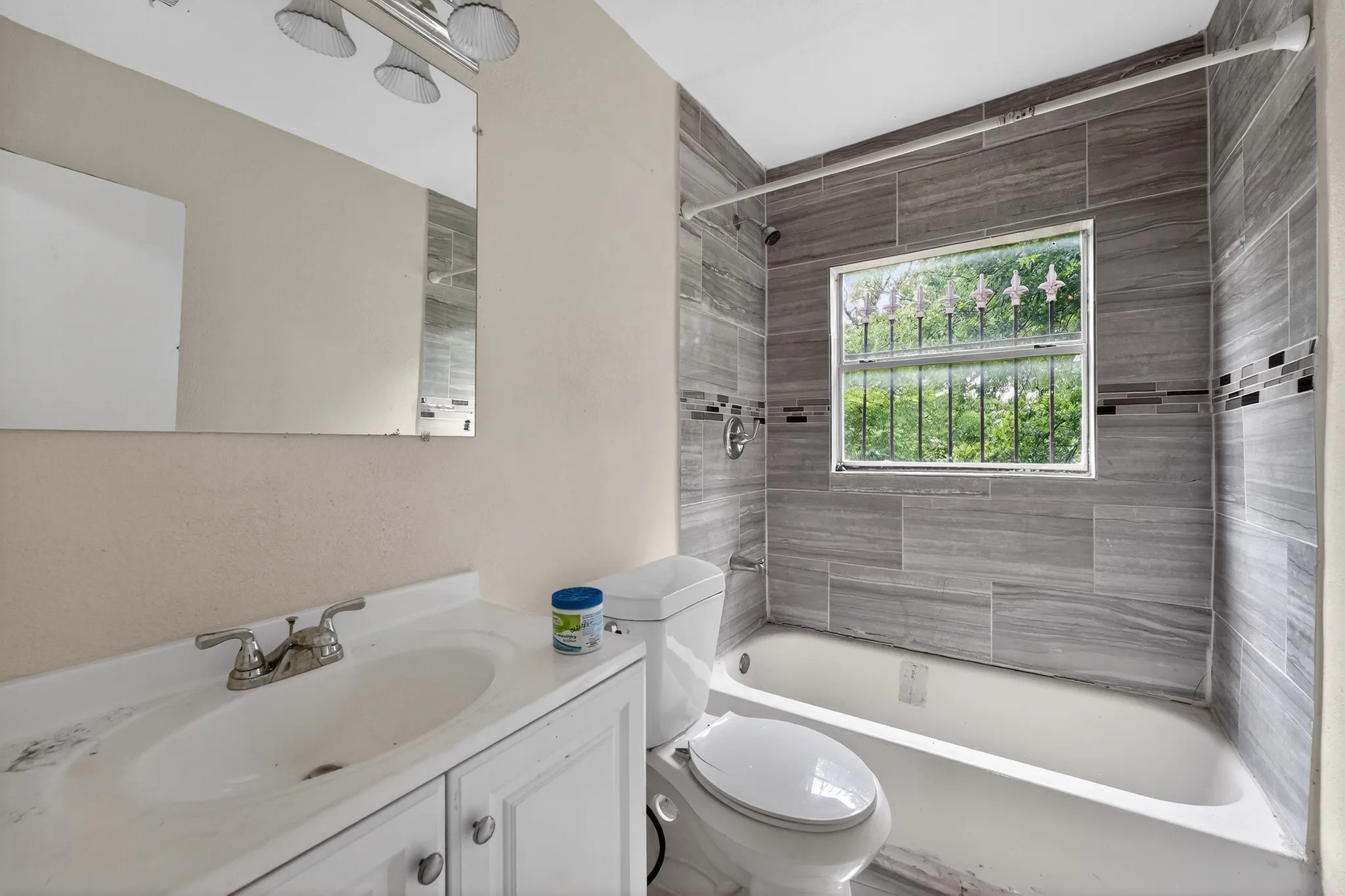 Bathroom featuring a white vanity with an integrated sink, a rectangular mirror, and a three-light fixture