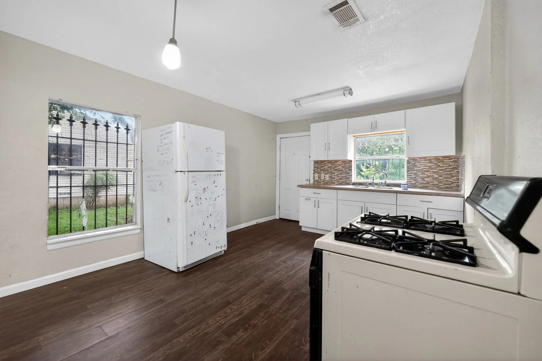 Kitchen featuring wood-finish flooring, white cabinetry, a neutral backsplash, and a built-in range