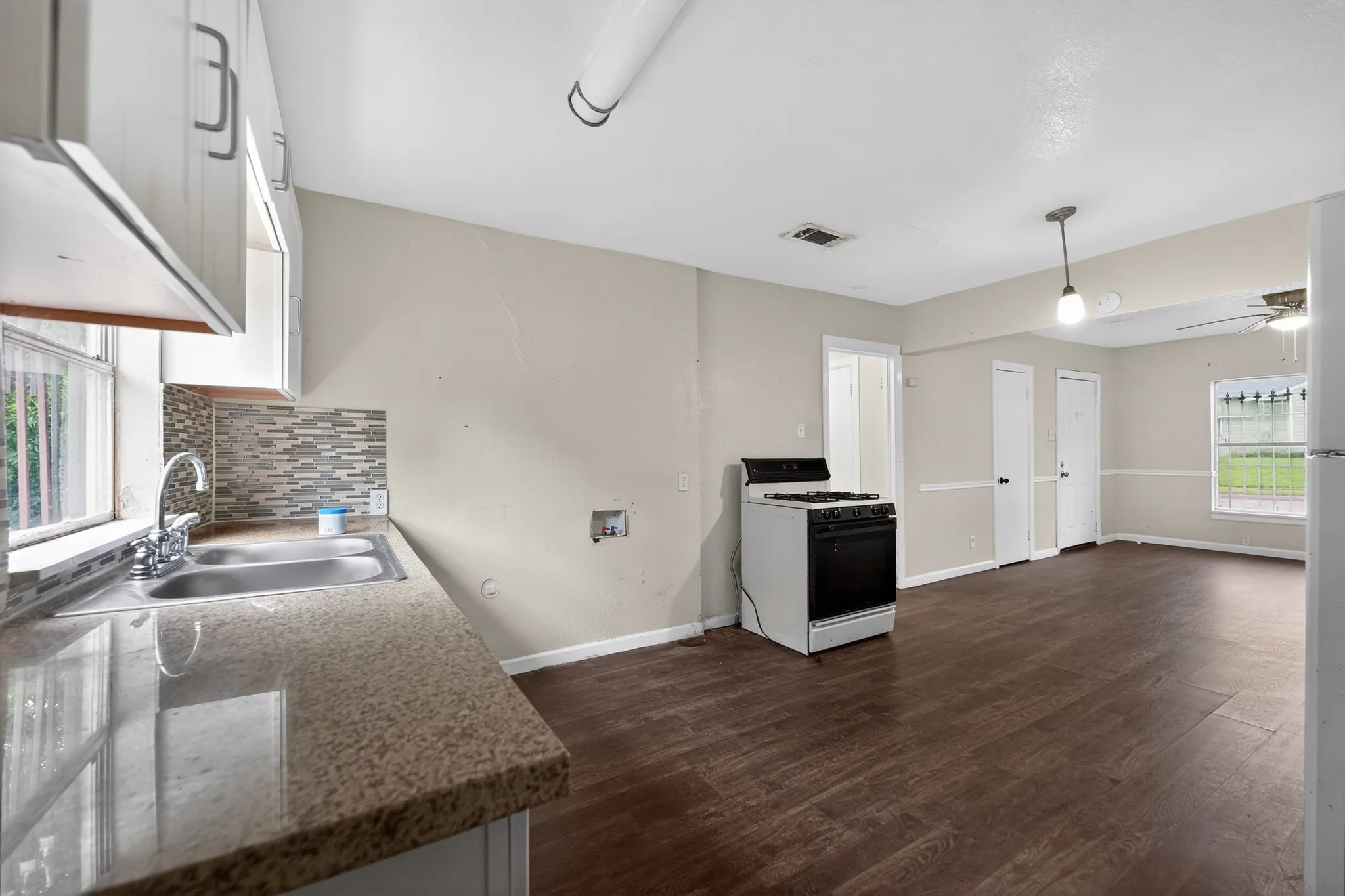 Kitchen area featuring a double basin stainless steel sink, tile backsplash, and light-toned countertop