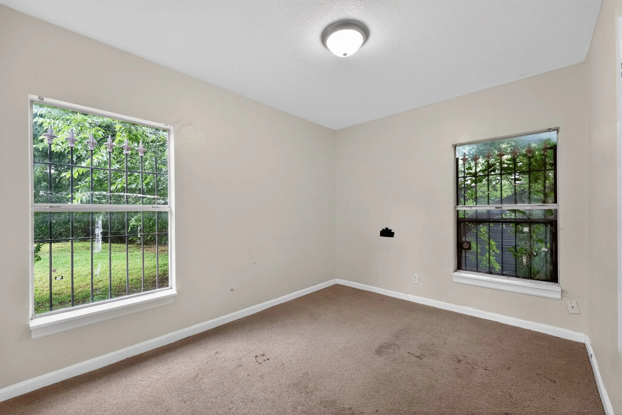 Spacious room featuring neutral painted walls, carpeted flooring, and a flush-mount ceiling light fixture