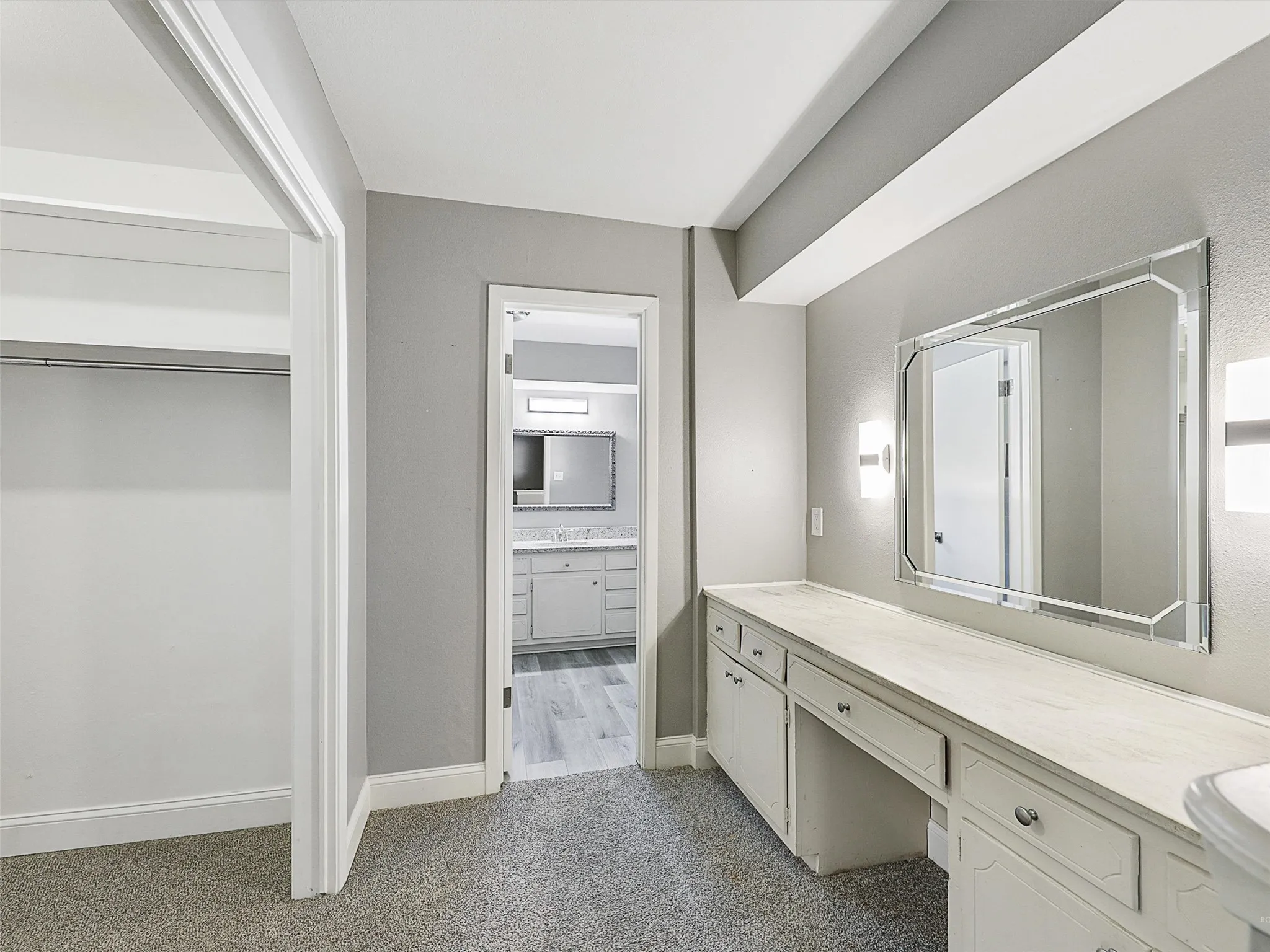 Dedicated dressing area with built-in vanity, oversized mirror, and direct access to the primary bath and walk-in closet.