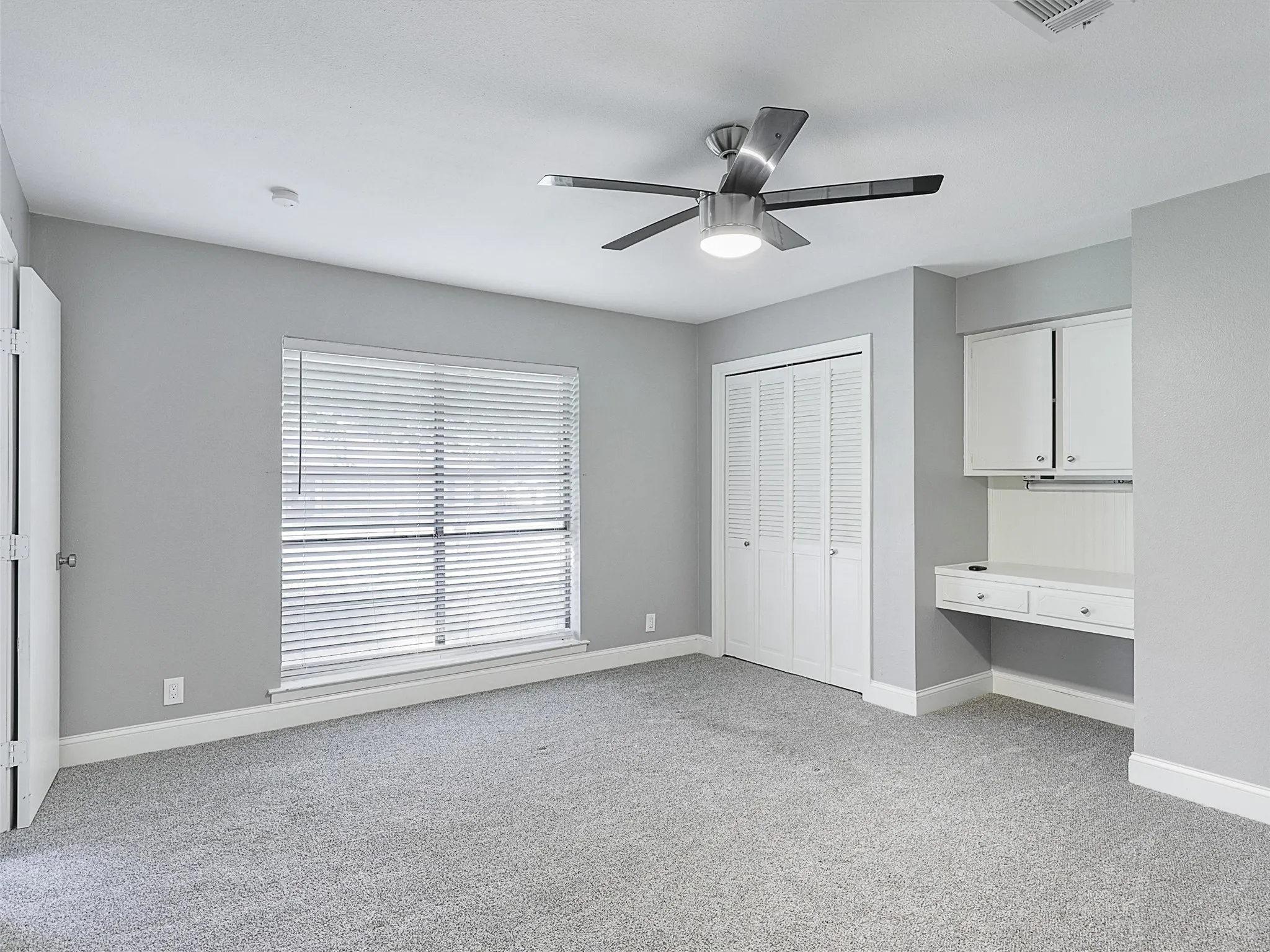 Comfortable secondary bedroom with abundant natural light, built-in desk area, and flexible space for work, study, or guests.