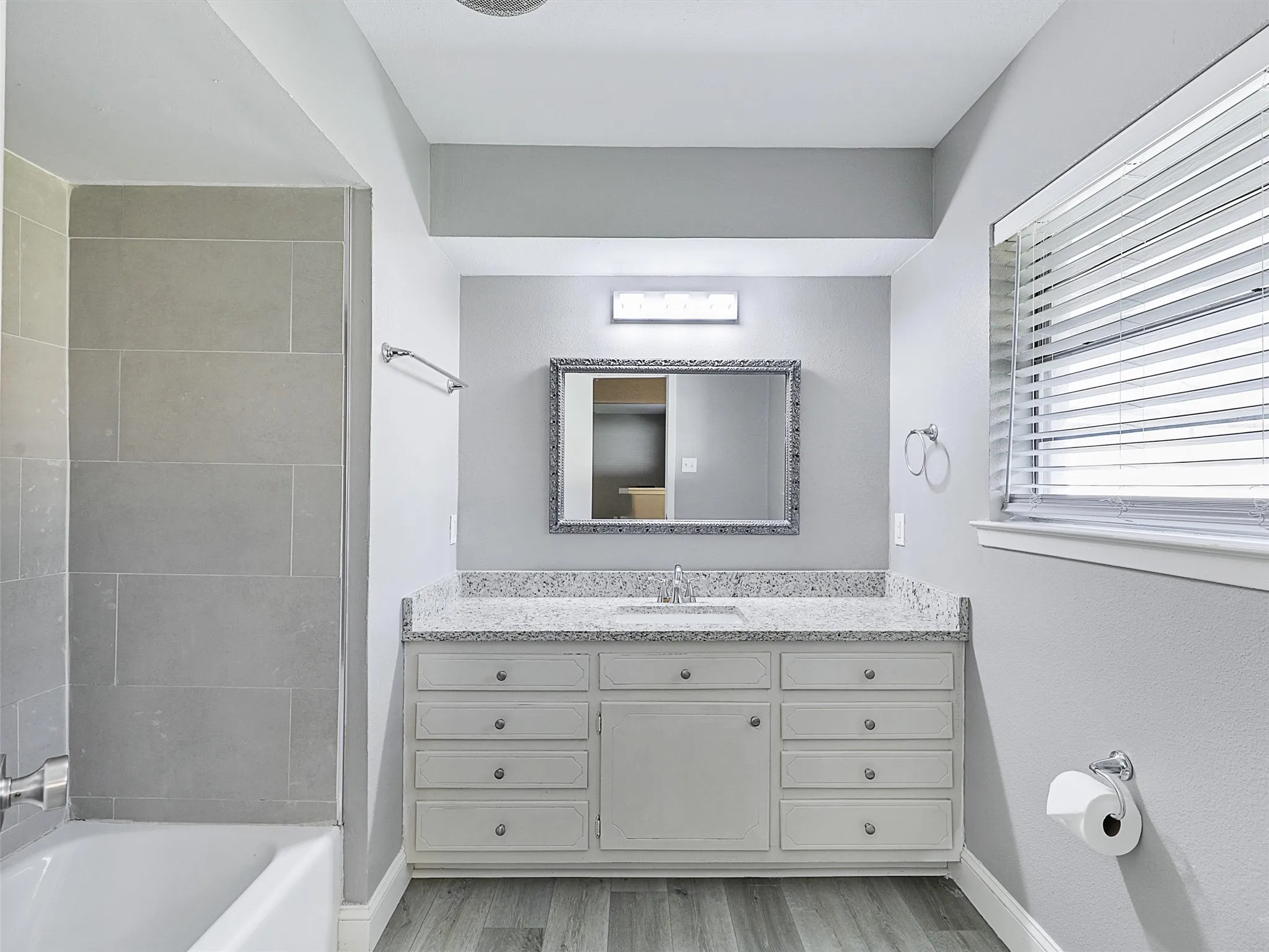 Primary Bathroom
Updated primary bath featuring granite countertops, generous storage, and a spacious tub-shower combination.