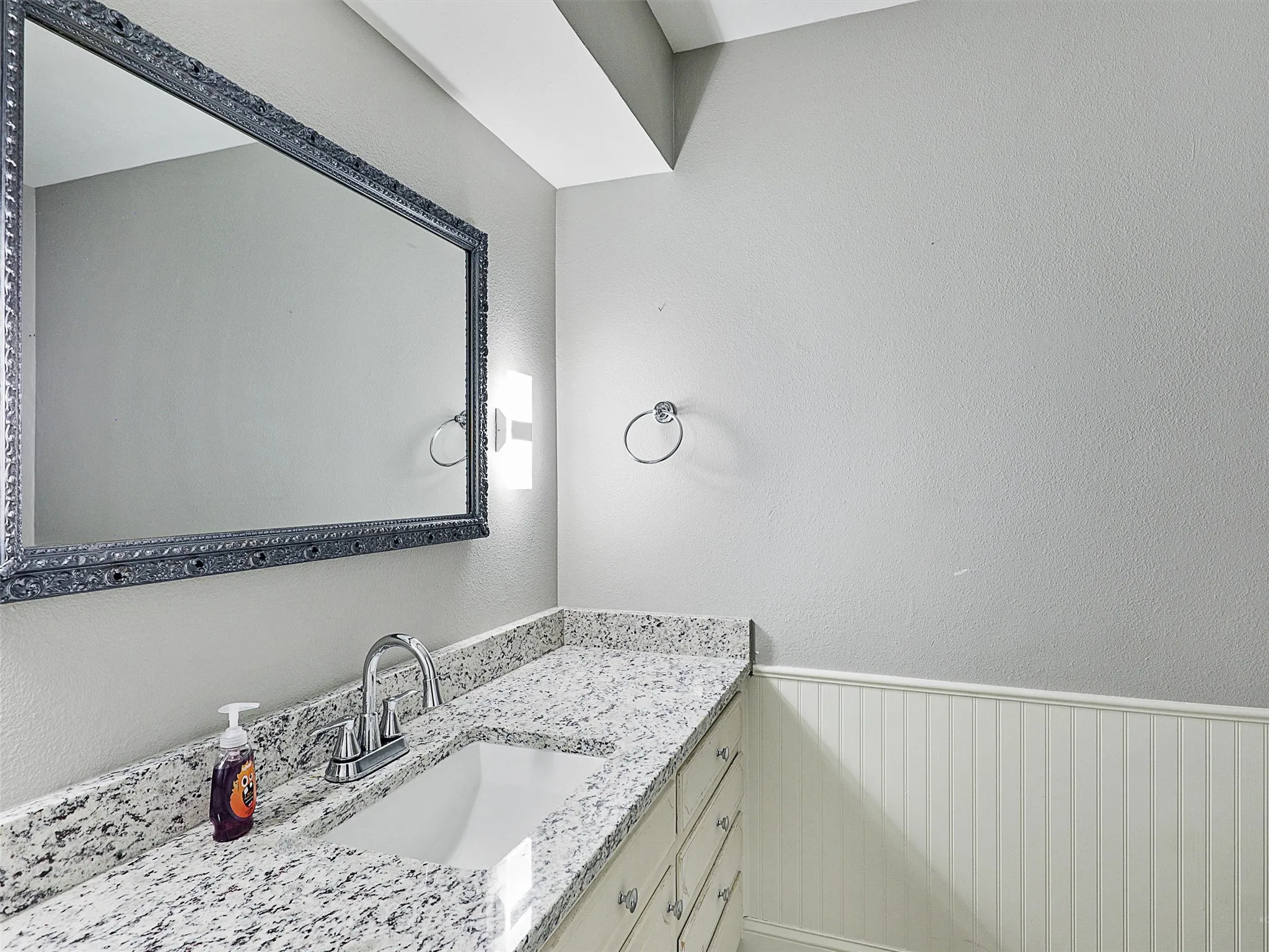 Conveniently located powder bath with granite countertops and updated fixtures for guests.