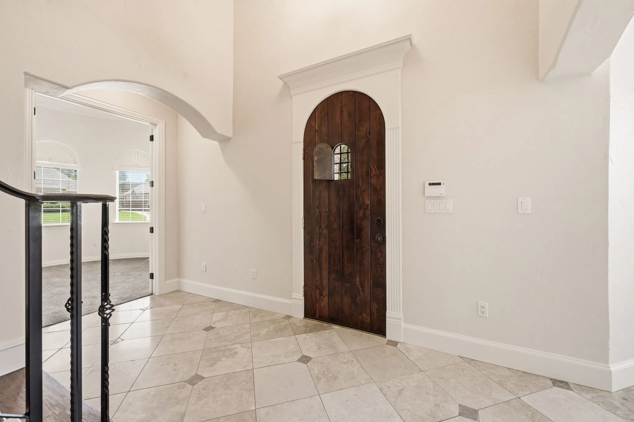 Beautiful sold wood door with view port, travertine floors and iron balustrade